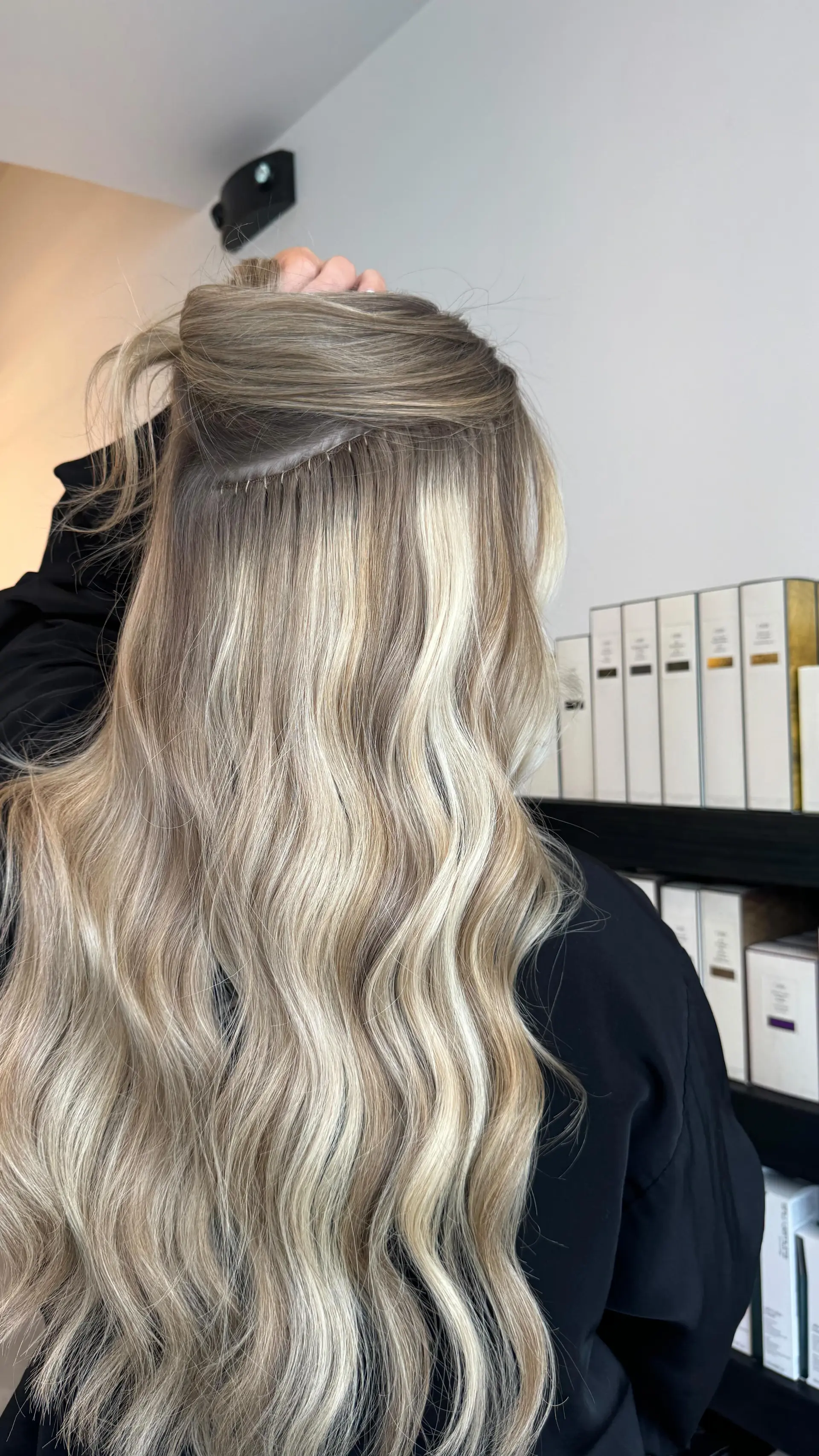 Long dimensional blonde hair styled in soft waves, featuring seamless weft hair extensions. 1