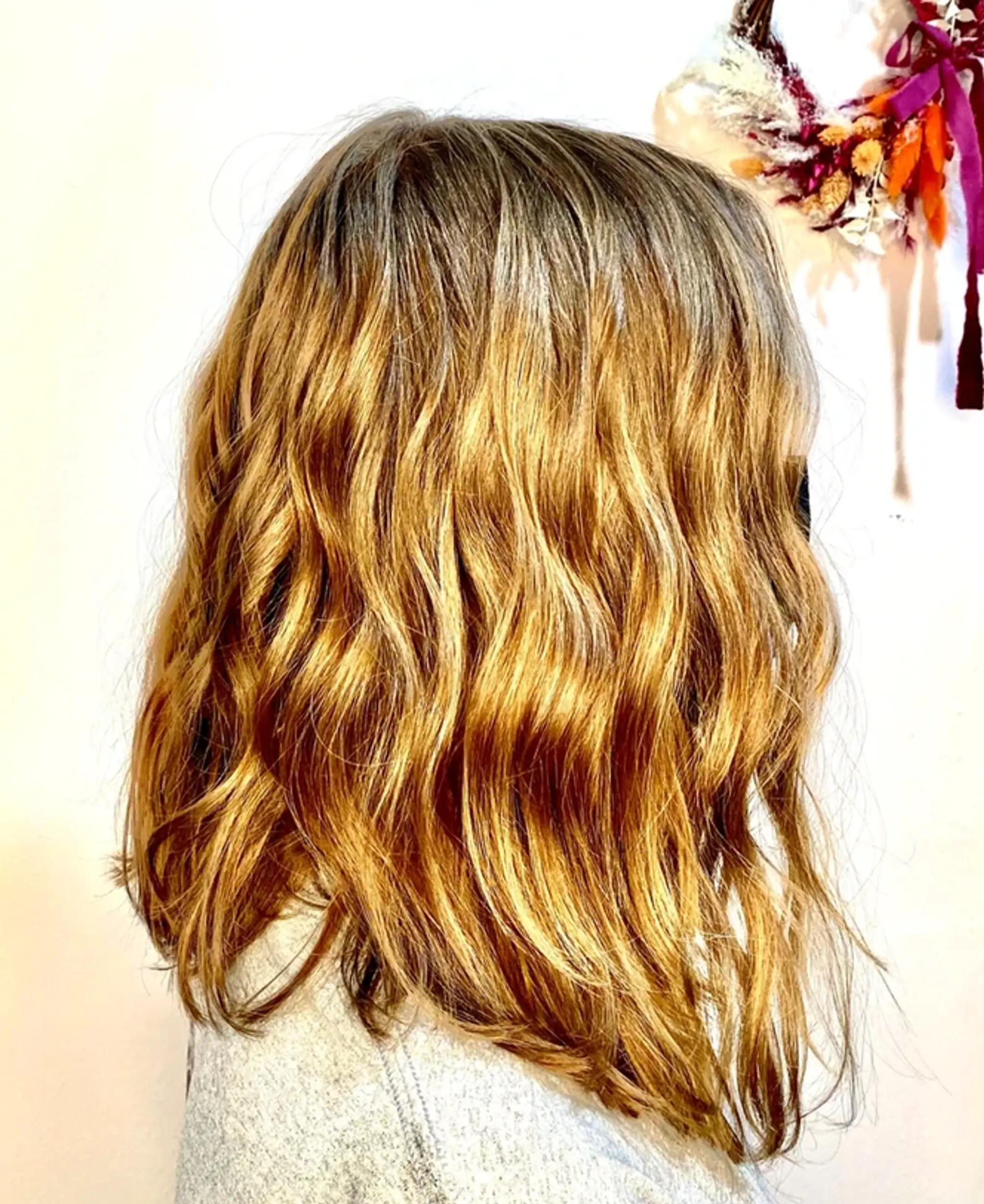 Medium-length wavy hairstyle with honey blonde hues, featuring natural waves and layered ends for a soft, flowing look.