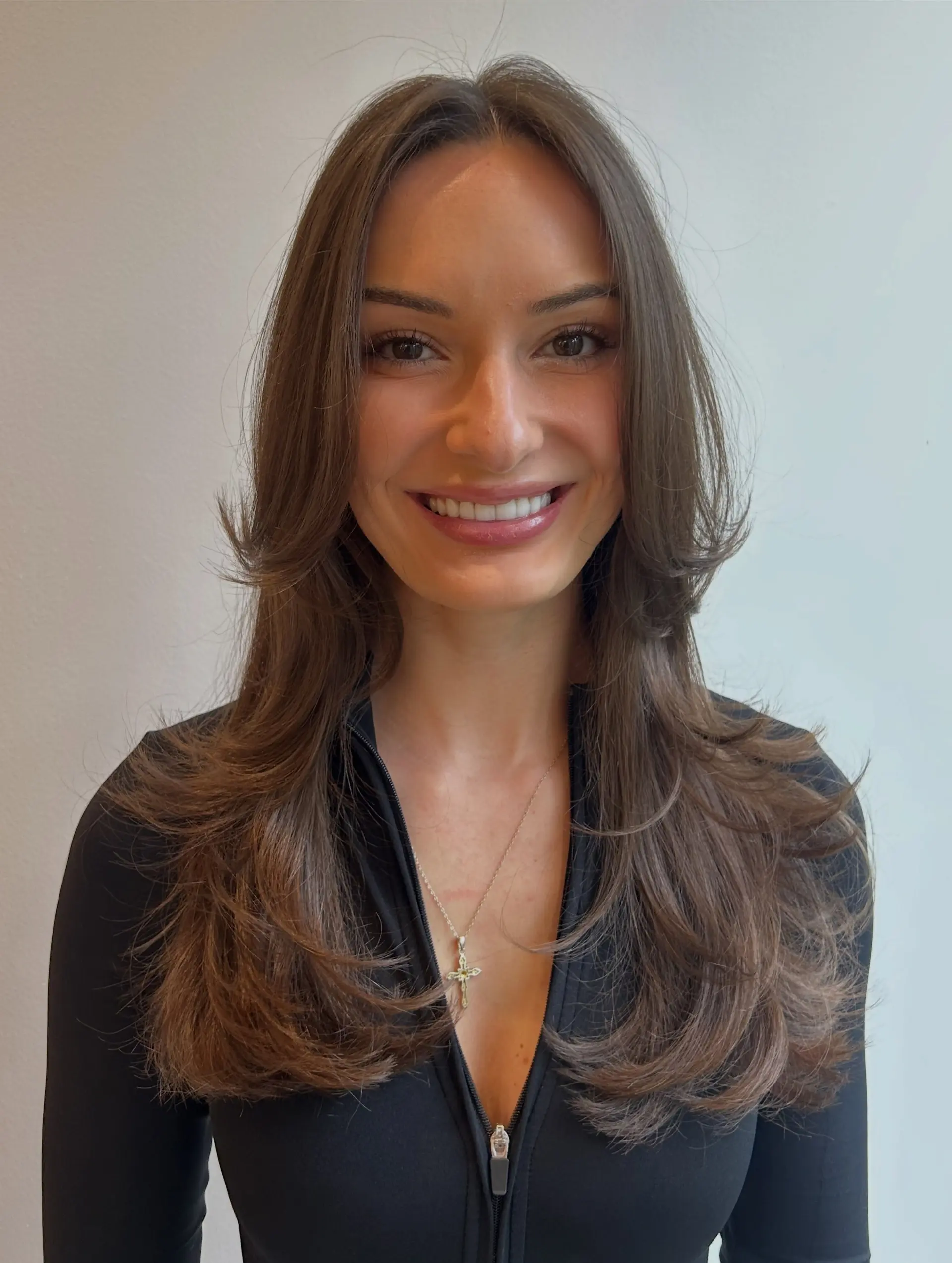 A long, richly toned brunette cut featuring cascading face-framing layers styled with flipped-out, voluminous ends for a bouncy, glossy finish. 1
