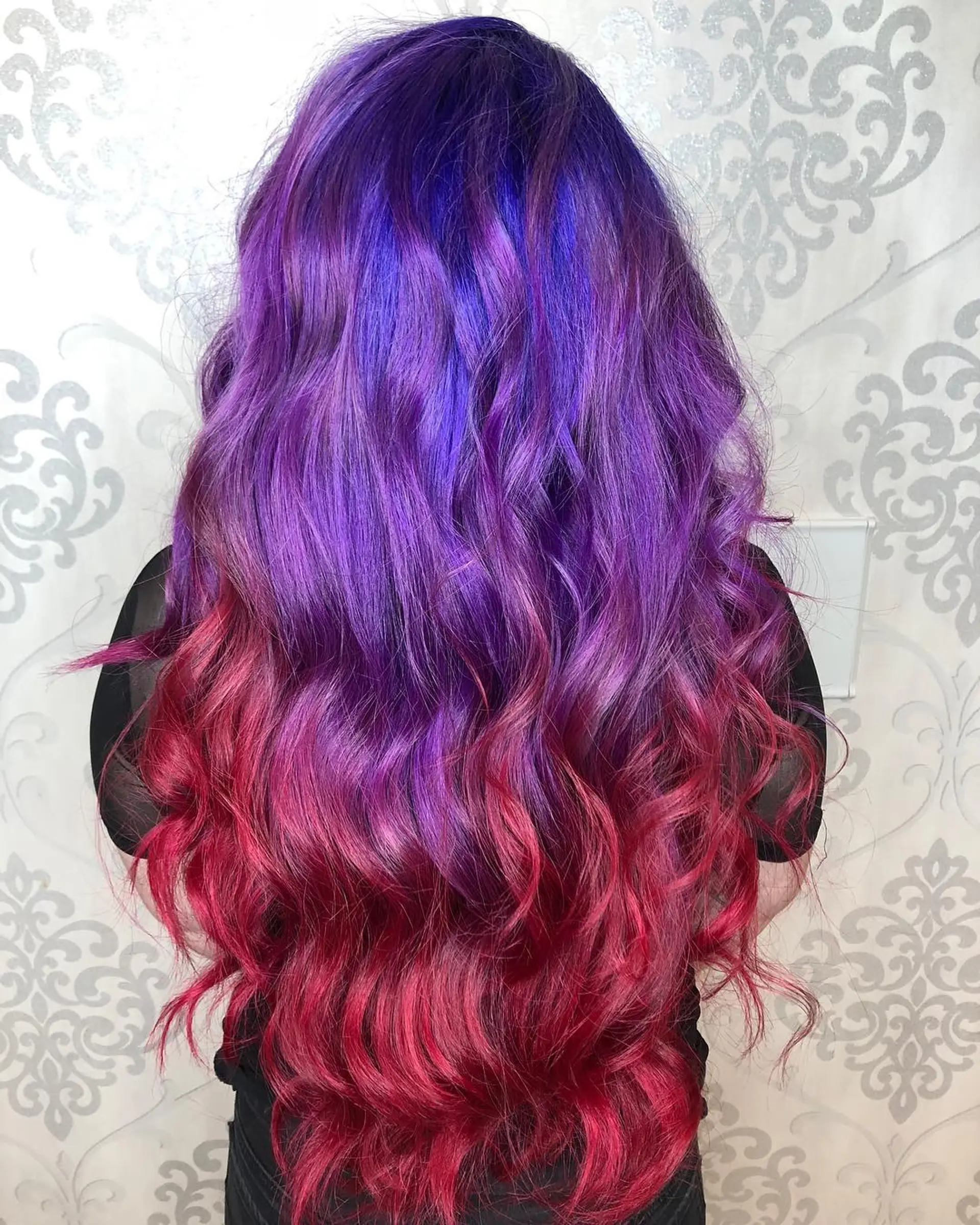 Extra-long hair featuring a dramatic vivid color melt transitioning from deep purple and violet roots to vibrant magenta-pink ends, styled in loose cascading waves. 1