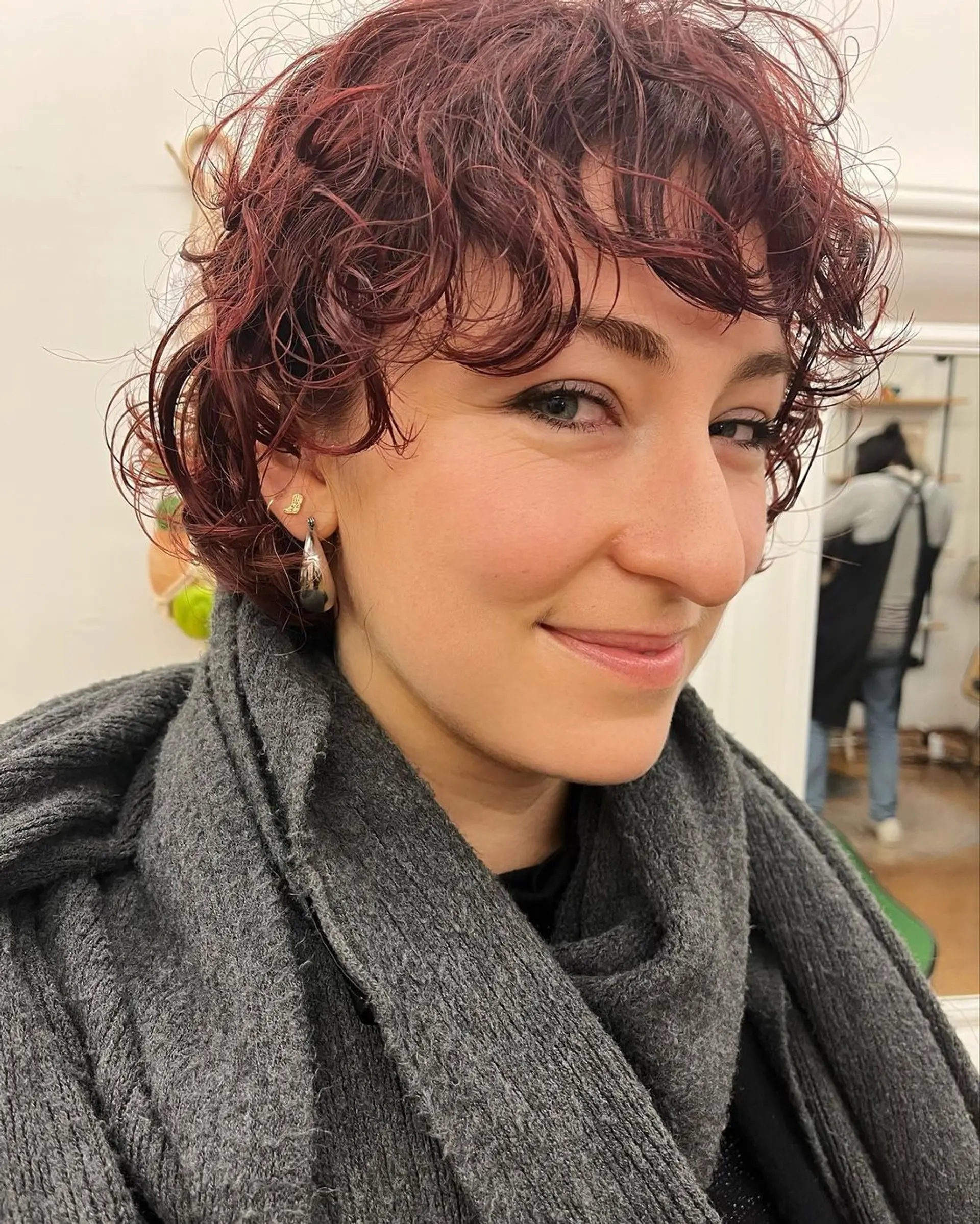 Short, dark red curly bob with bouncy curls, textured layers, and a side-swept fringe. 1