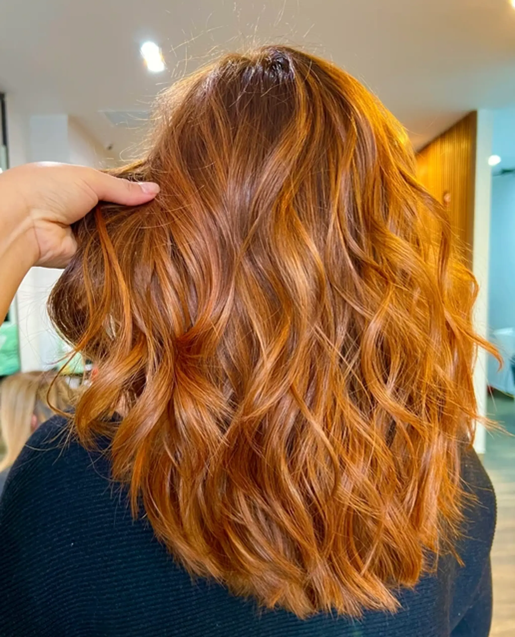 Medium-length wavy hair with vibrant copper and golden blonde tones, featuring loose waves for a full-bodied look.
