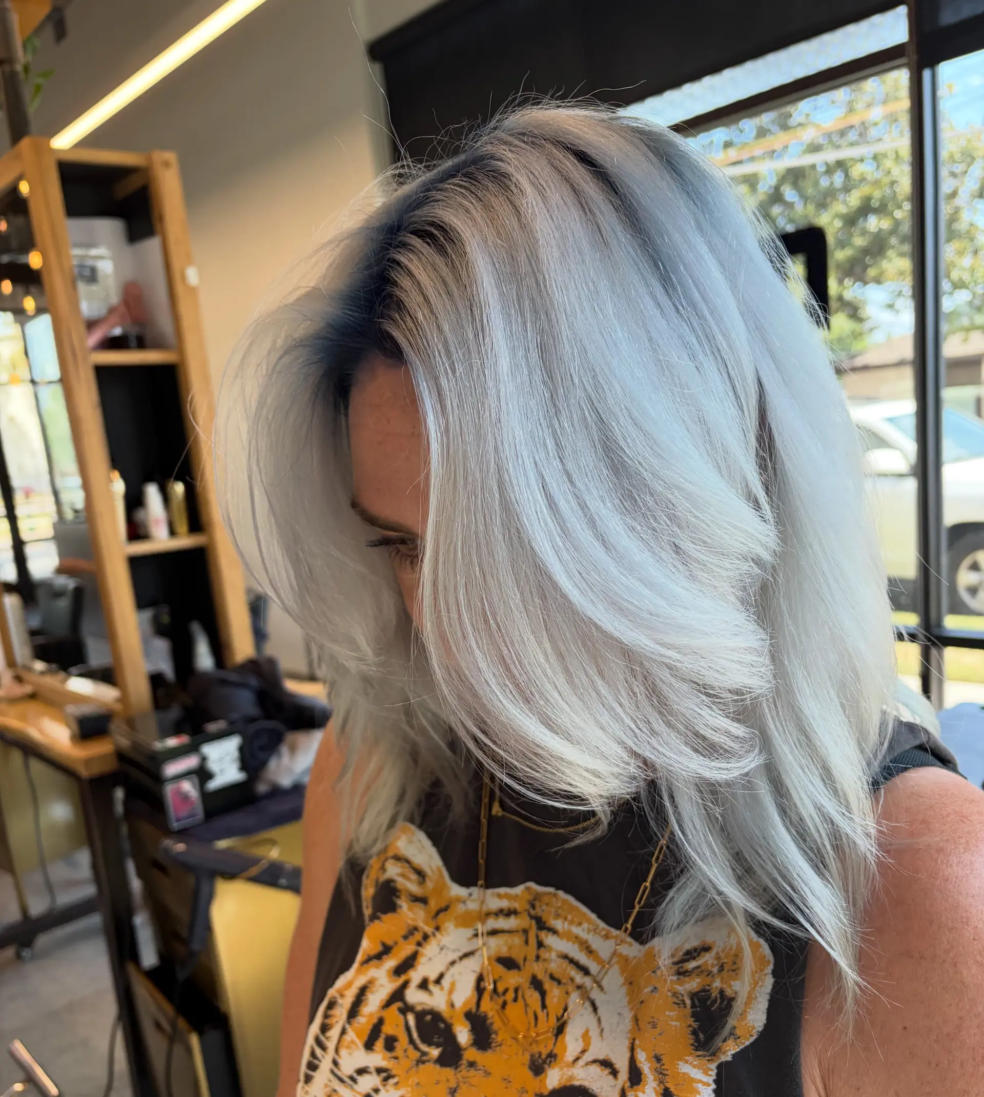 Icy platinum blonde medium-length hair with a dark shadow root and voluminous face-framing layers. 1