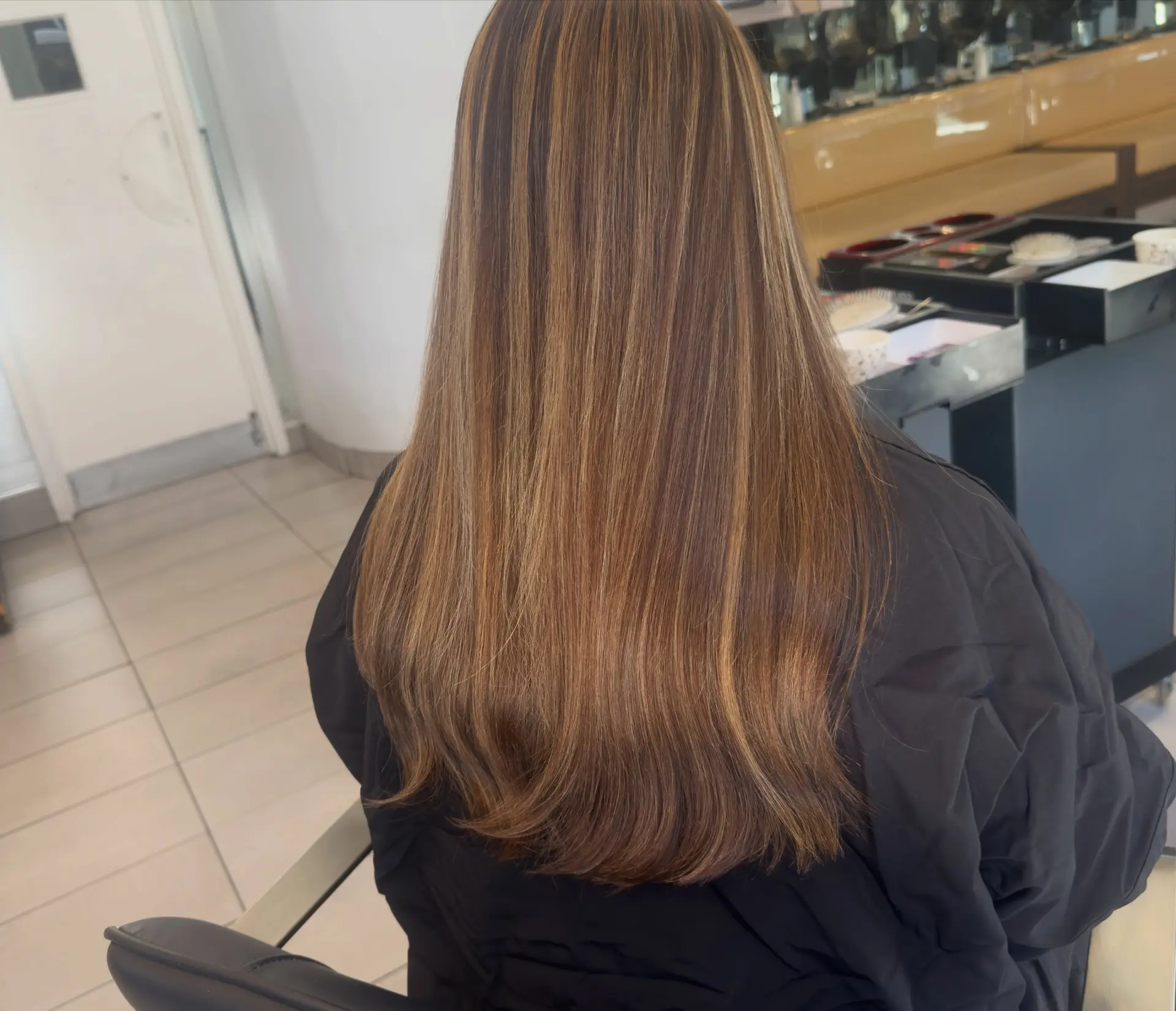 Long, smooth straight hair featuring dimensional caramel highlights woven throughout a rich brown base, finished with soft turned-under ends. 1
