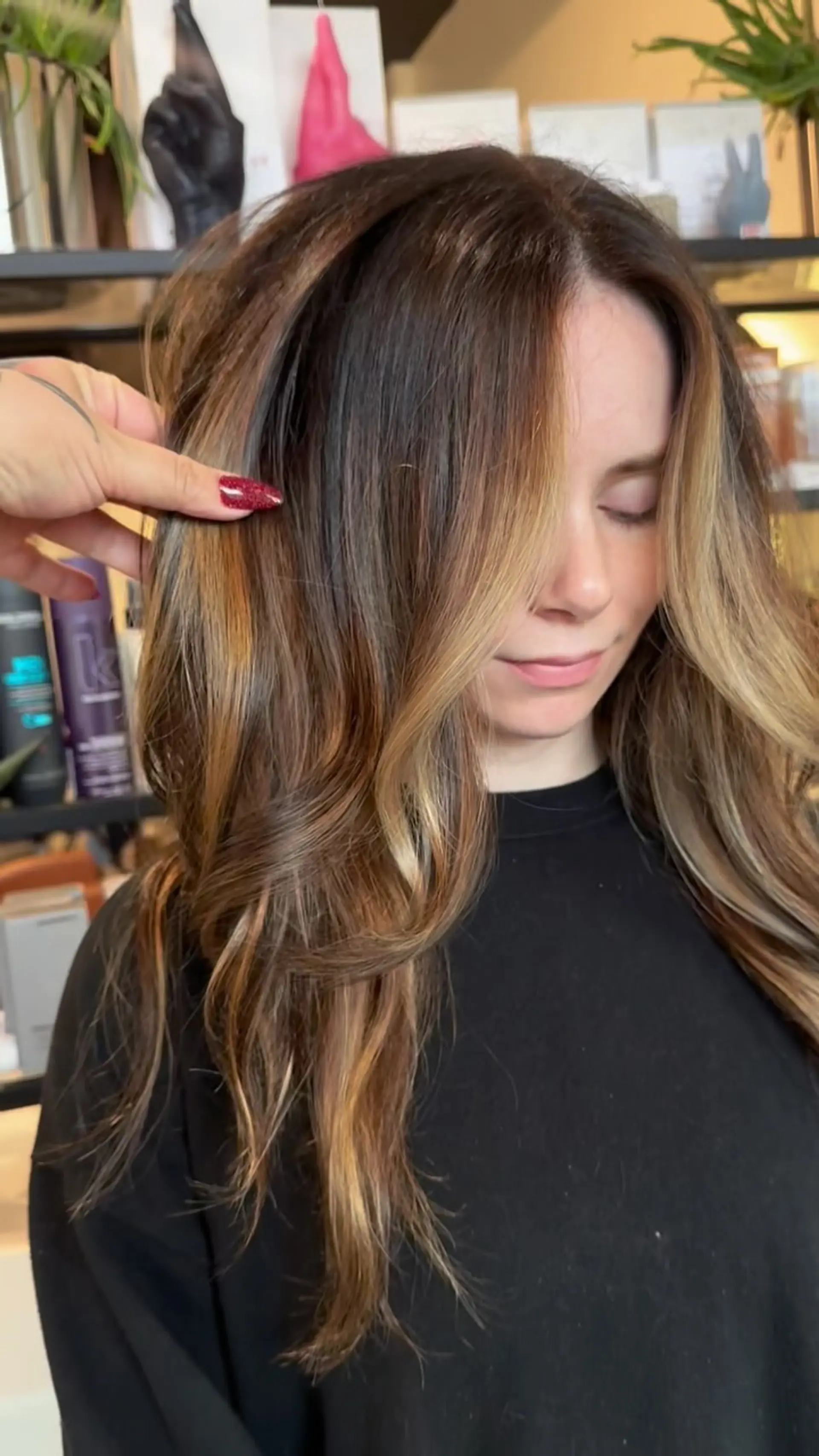 Rich brunette hair enhanced with caramel and honey balayage and bright face-framing highlights, styled into soft waves. 1