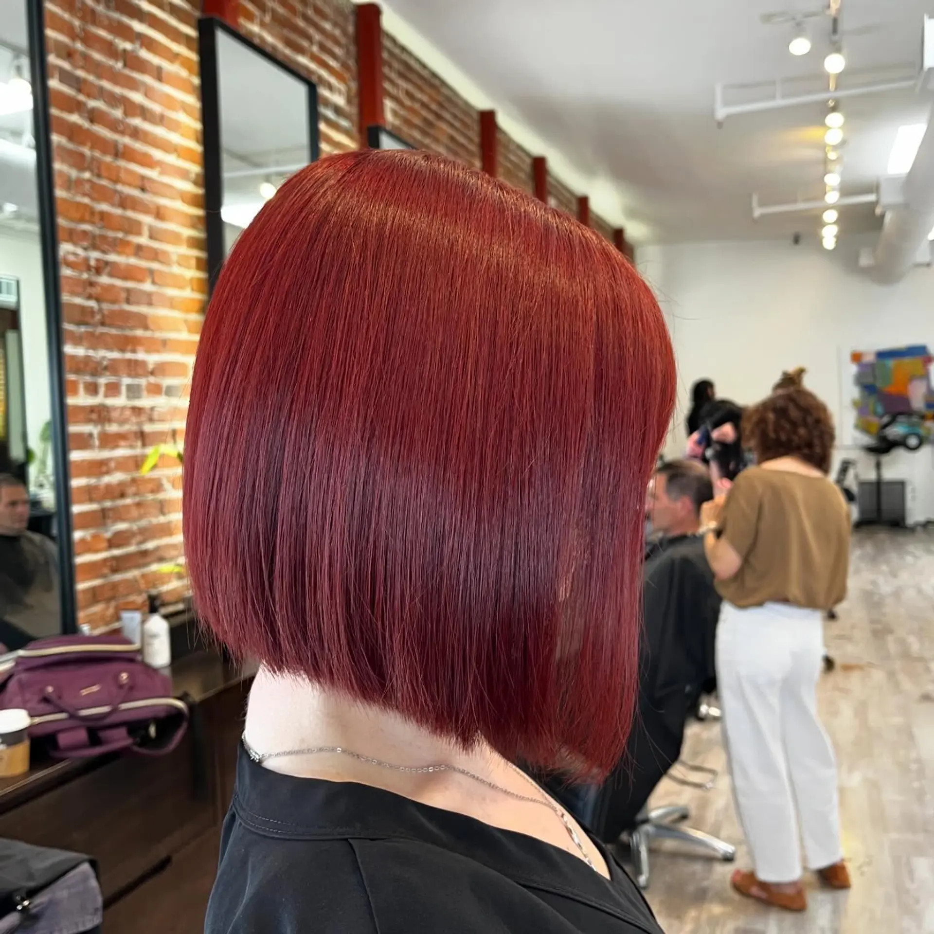 A sleek, straight angled bob haircut featuring a sharp, precision perimeter and a bold, vibrant crimson-red all-over color. 1