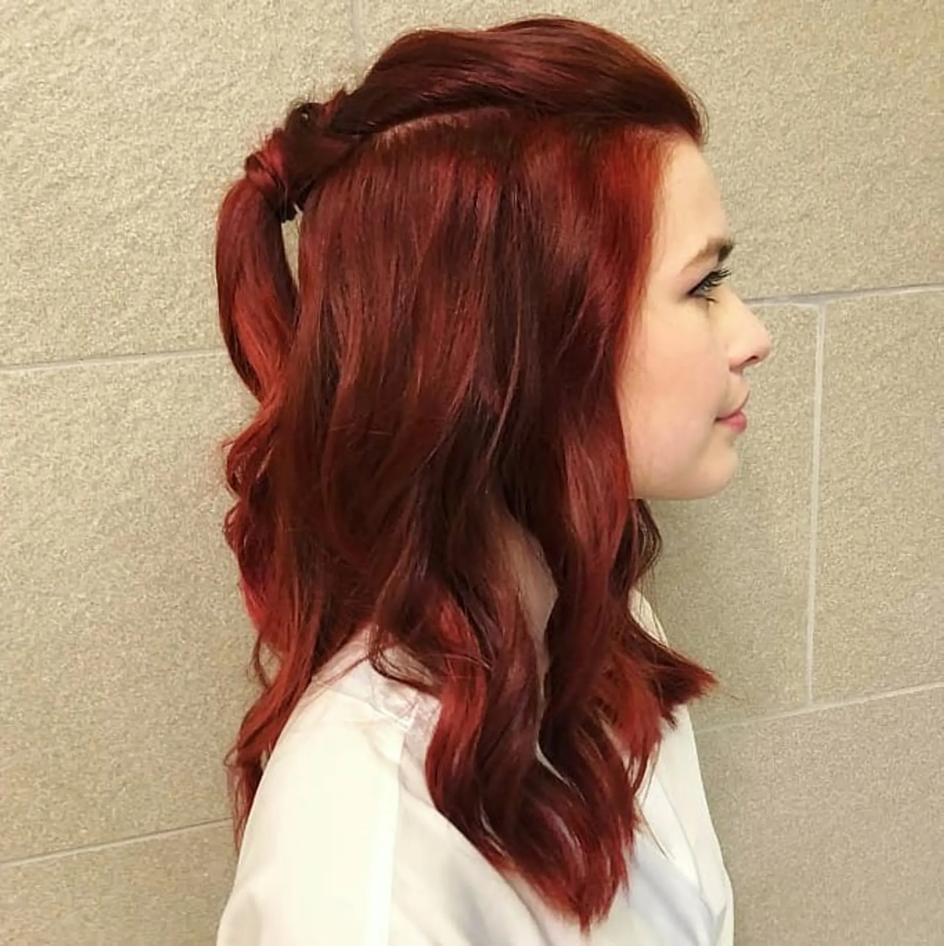 Medium-length vibrant red hair styled into soft loose waves with a textured half-up ponytail. 1