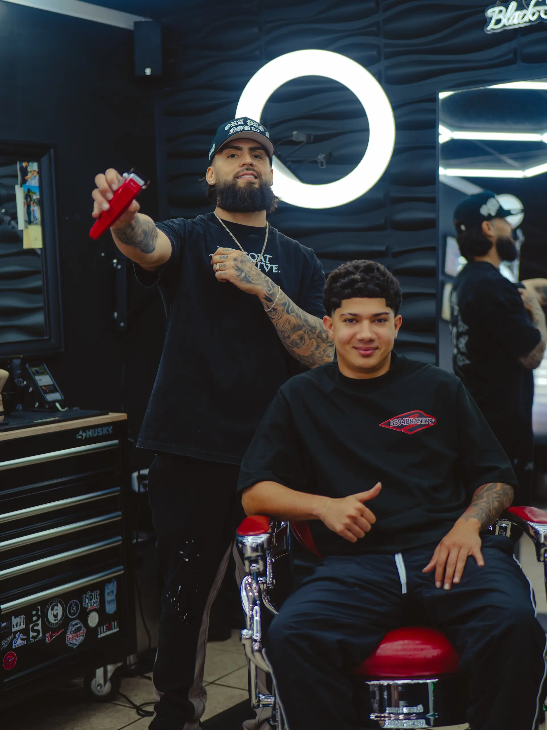 A modern men's short haircut with natural curl texture on top, a blunt forward fringe, and a crisp line up. 1
