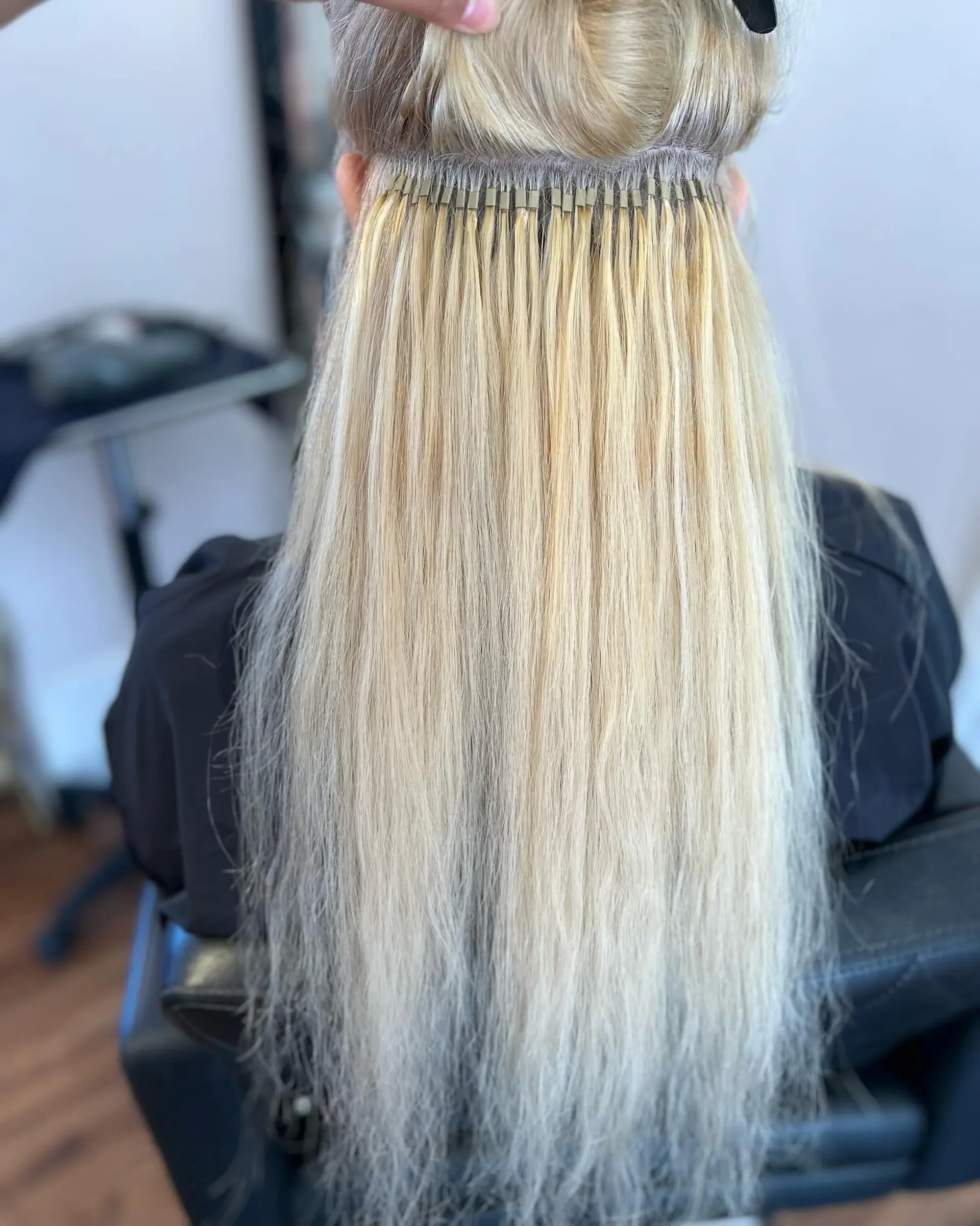 A meticulous row of blonde I-tip hair extensions cleanly installed along precise horizontal sections. 1