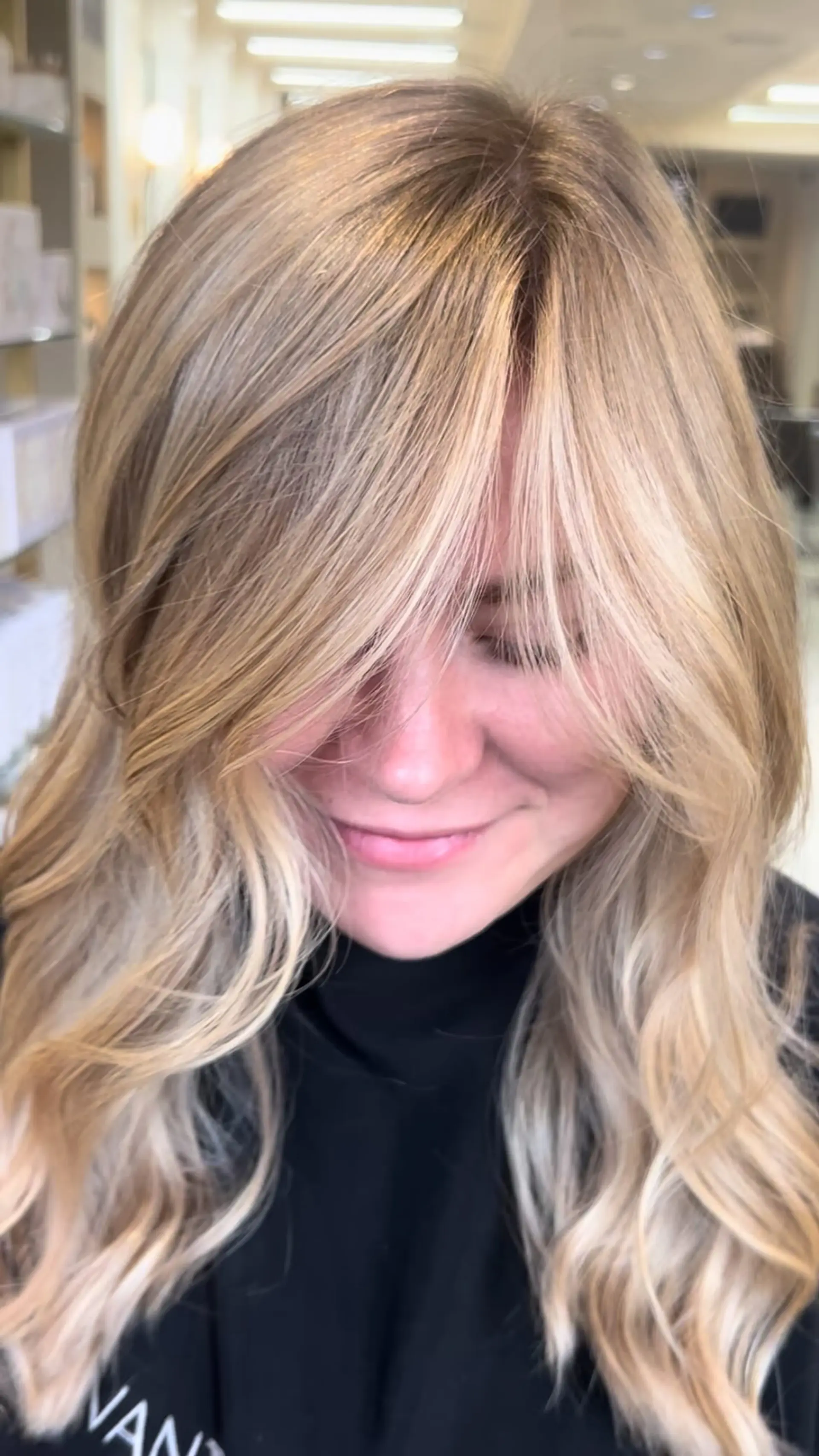 Soft dimensional blonde waves featuring long, face-framing curtain bangs. 1