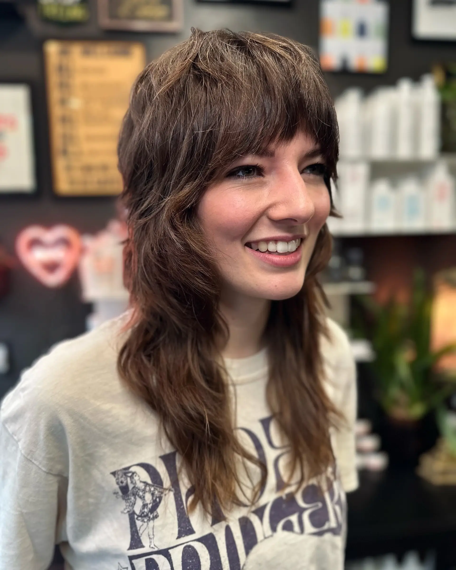 A layered brunette shag haircut featuring a choppy brow-length fringe and heavily textured, feathered face-framing layers. 1