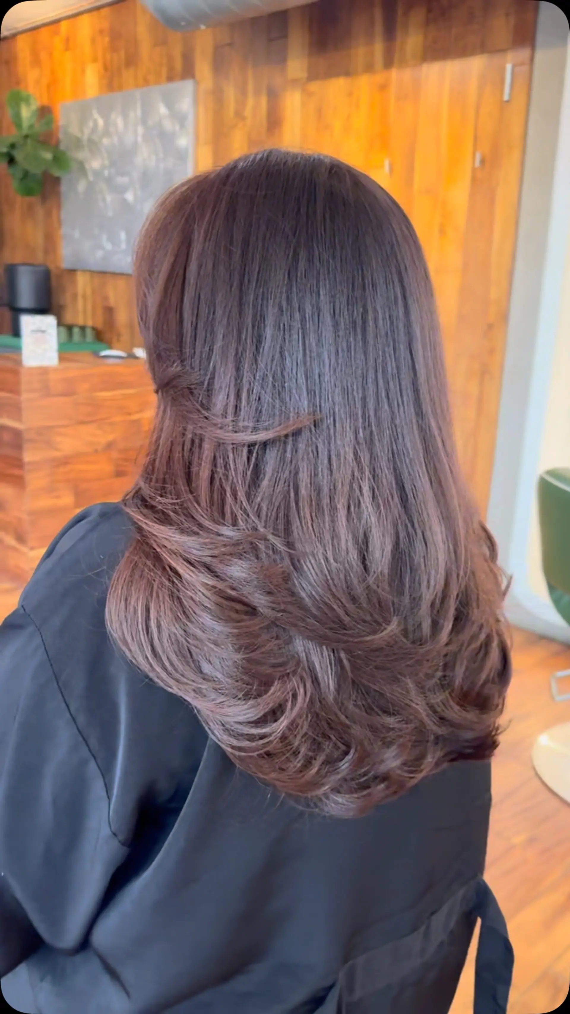 Long rich brunette layered haircut styled in a smooth, voluminous blowout with softly curved ends. 1
