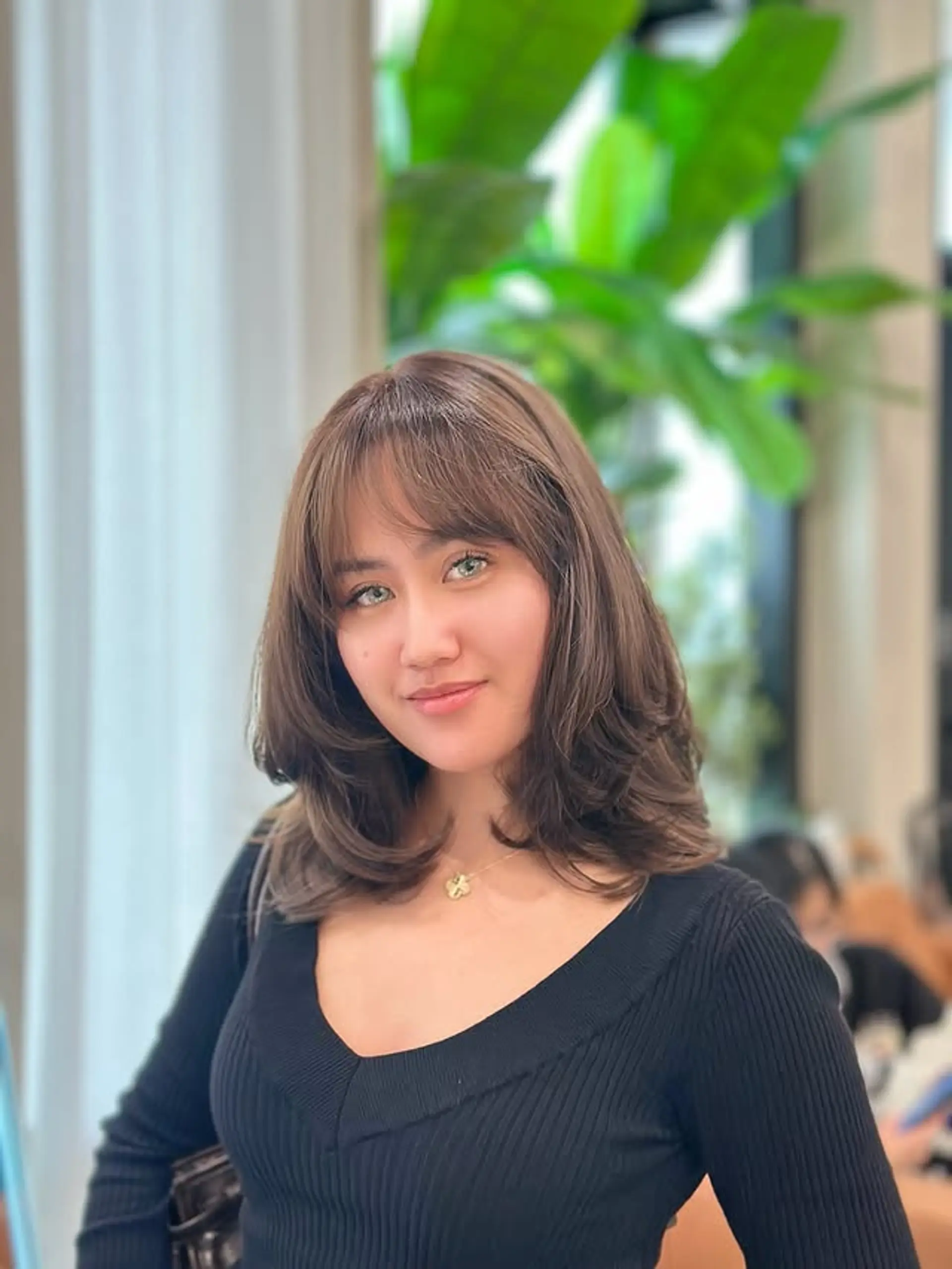 A layered medium-length haircut with face-framing layers and curtain bangs. 1