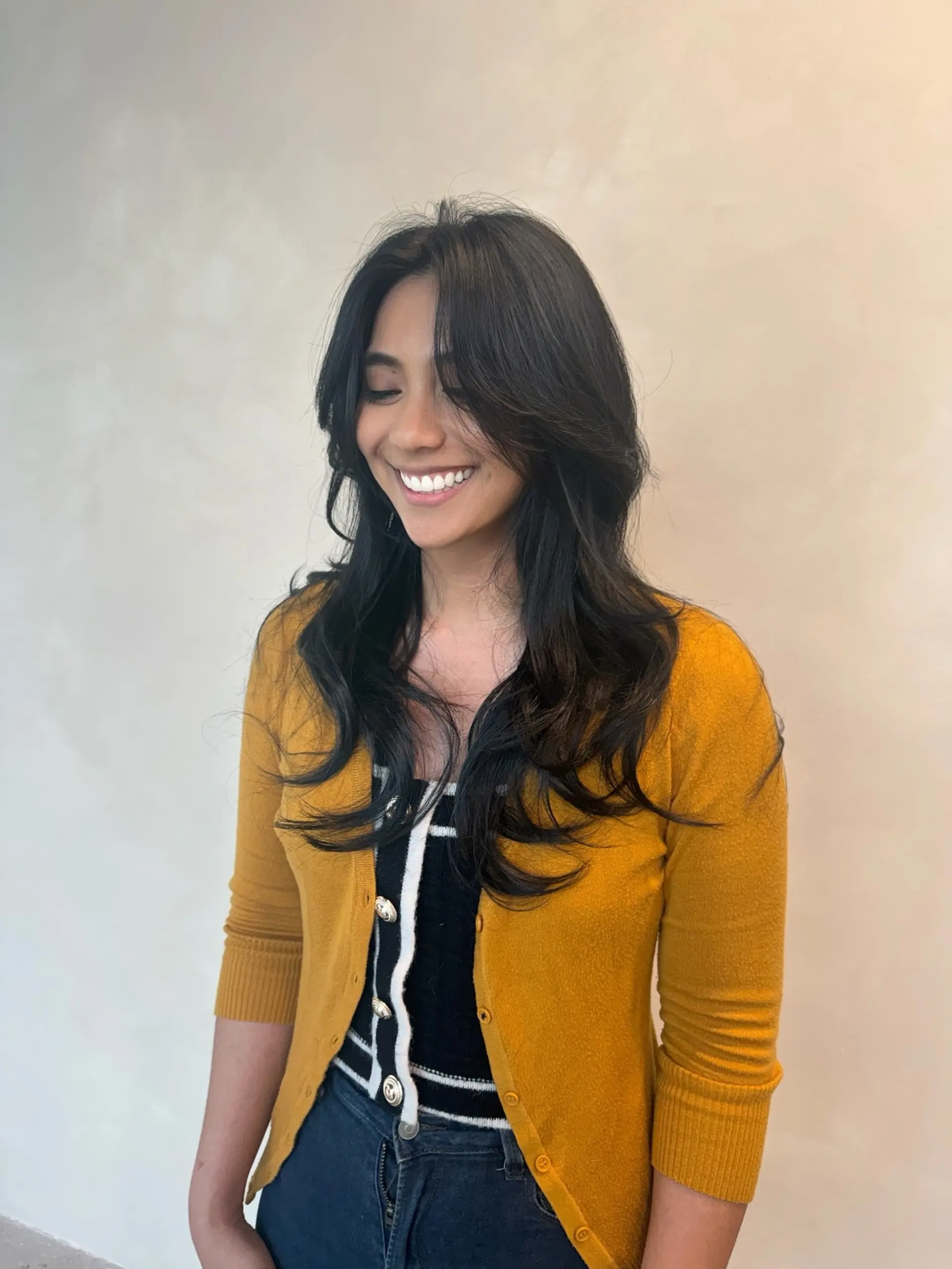 A long, textured layered haircut styled with sweeping curtain bangs and soft, voluminous waves. 1