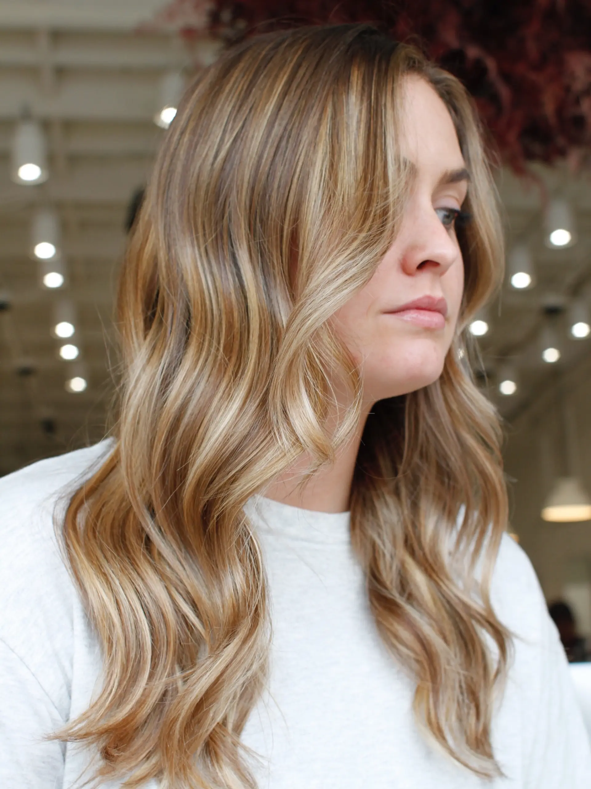 Long warm blonde hair featuring dimensional highlights styled into loose, gentle waves. 1