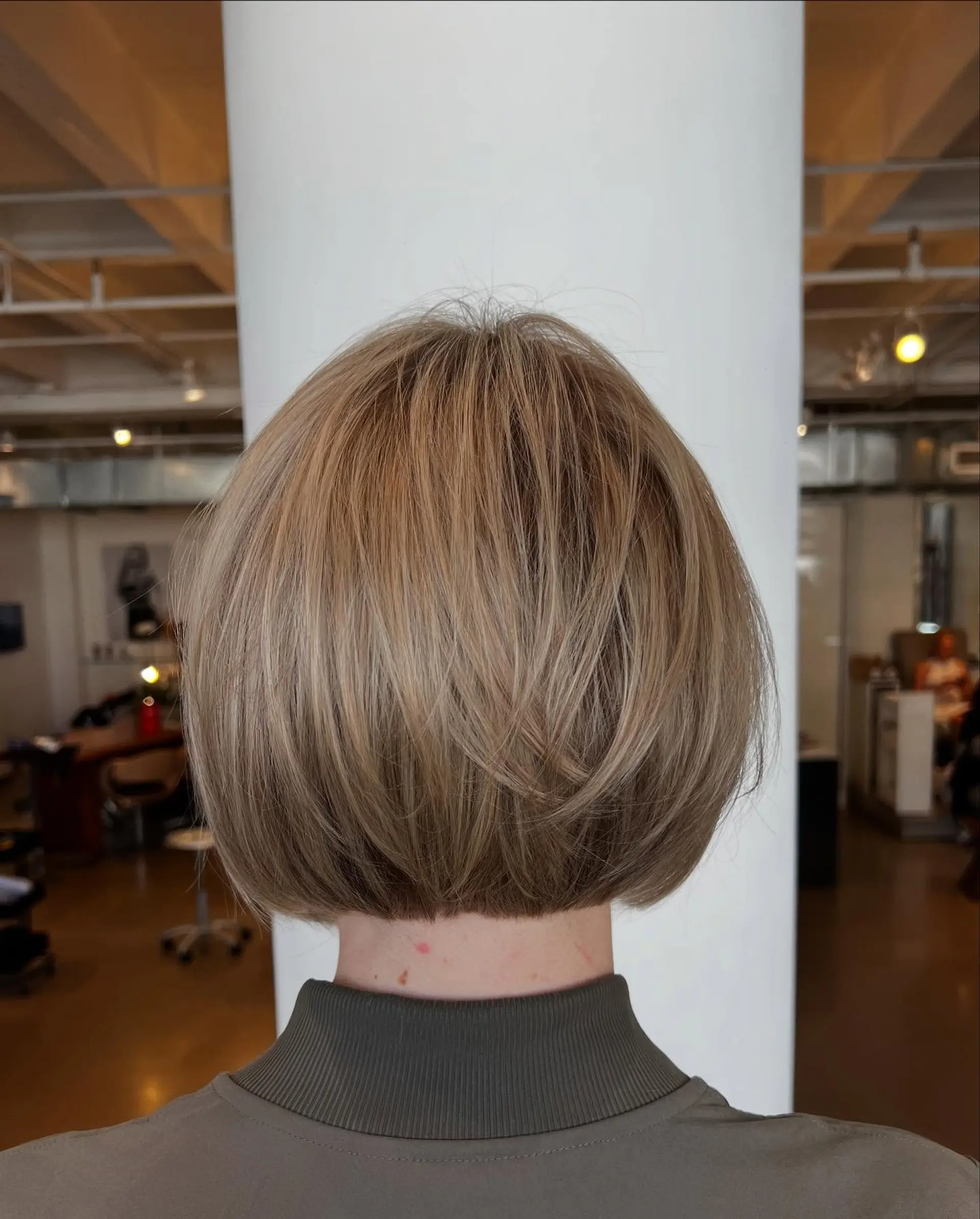 A precise, neck-length rounded bob haircut with subtle surface layers and dimensioned blonde tones. 1