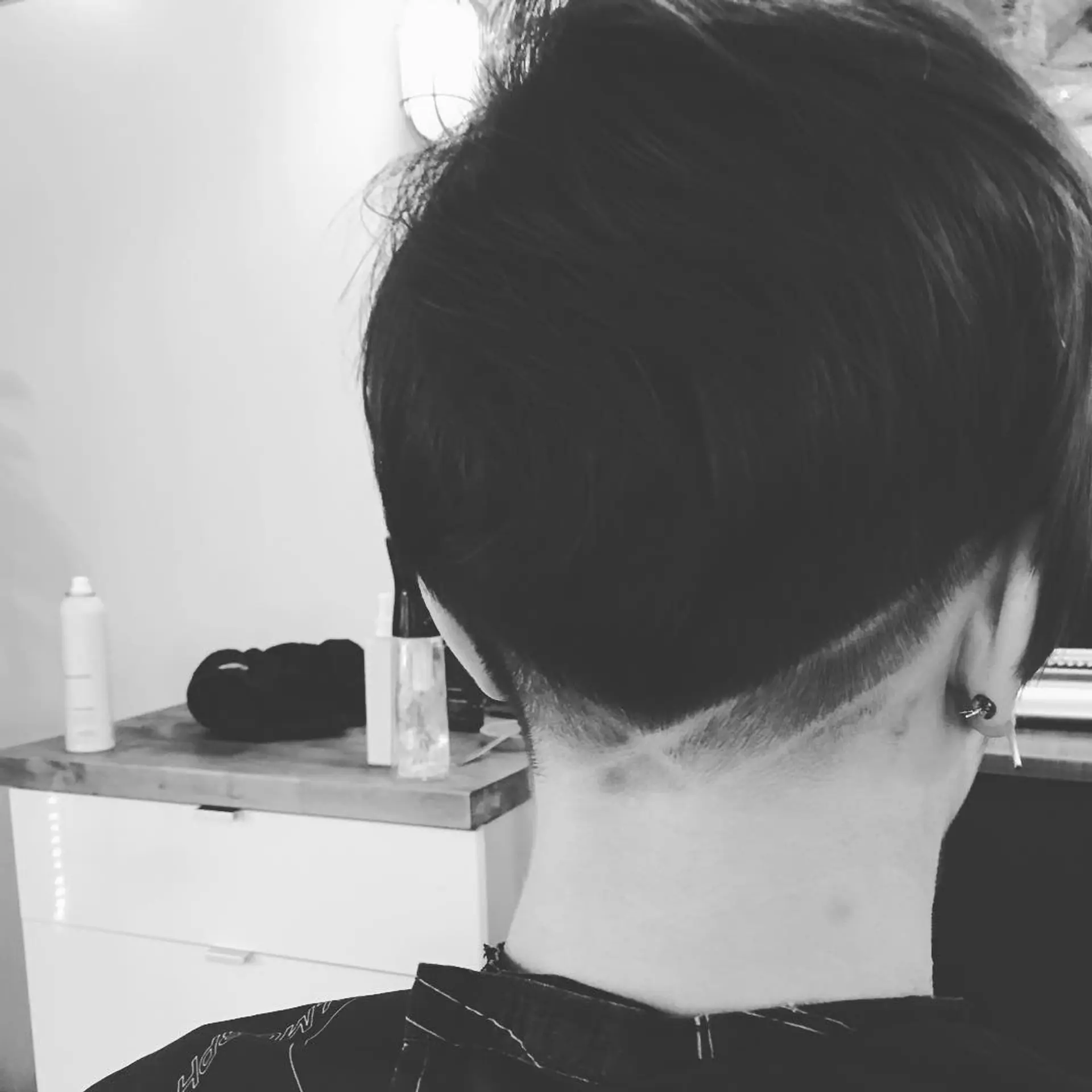 A sleek, short pixie haircut featuring a closely cropped nape undercut with subtle shaved geometric lines. 1