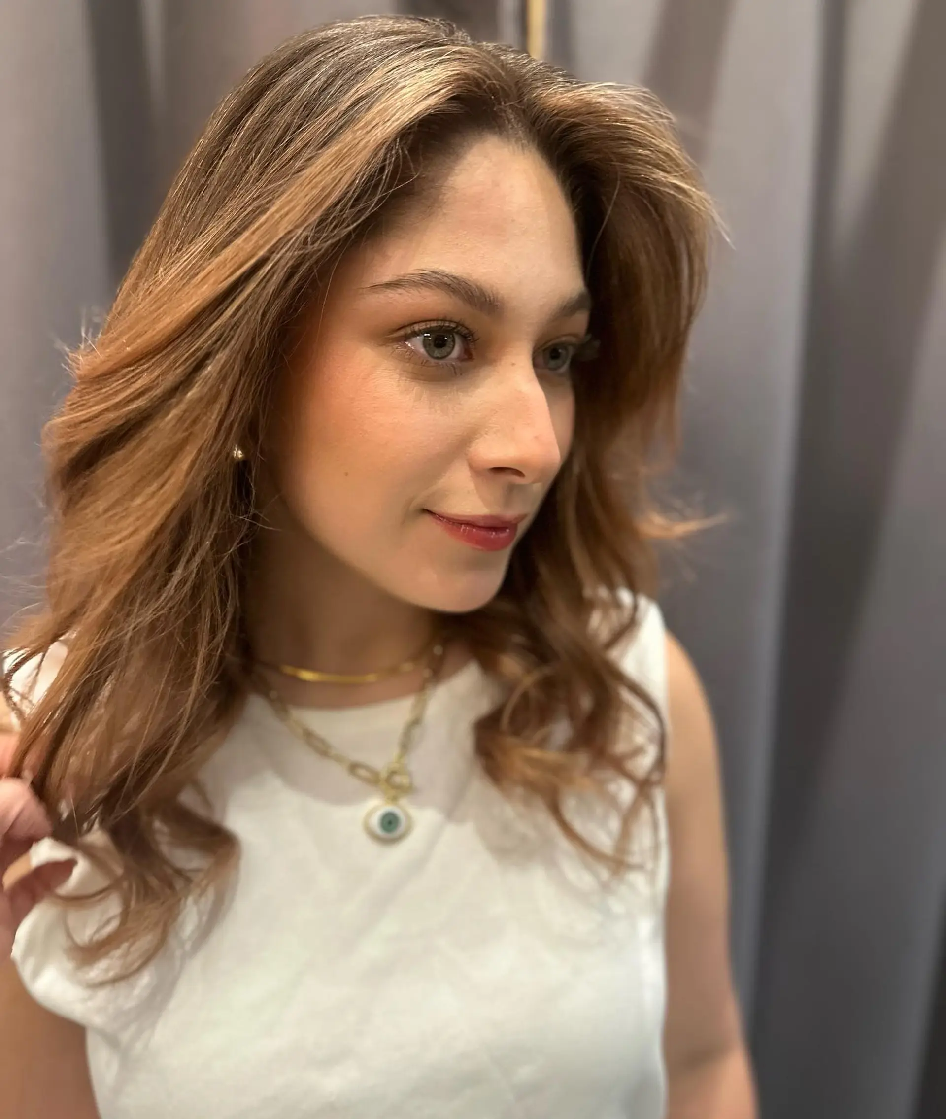Medium-length layered cut styled into voluminous, soft waves showcasing a warm copper balayage. 1