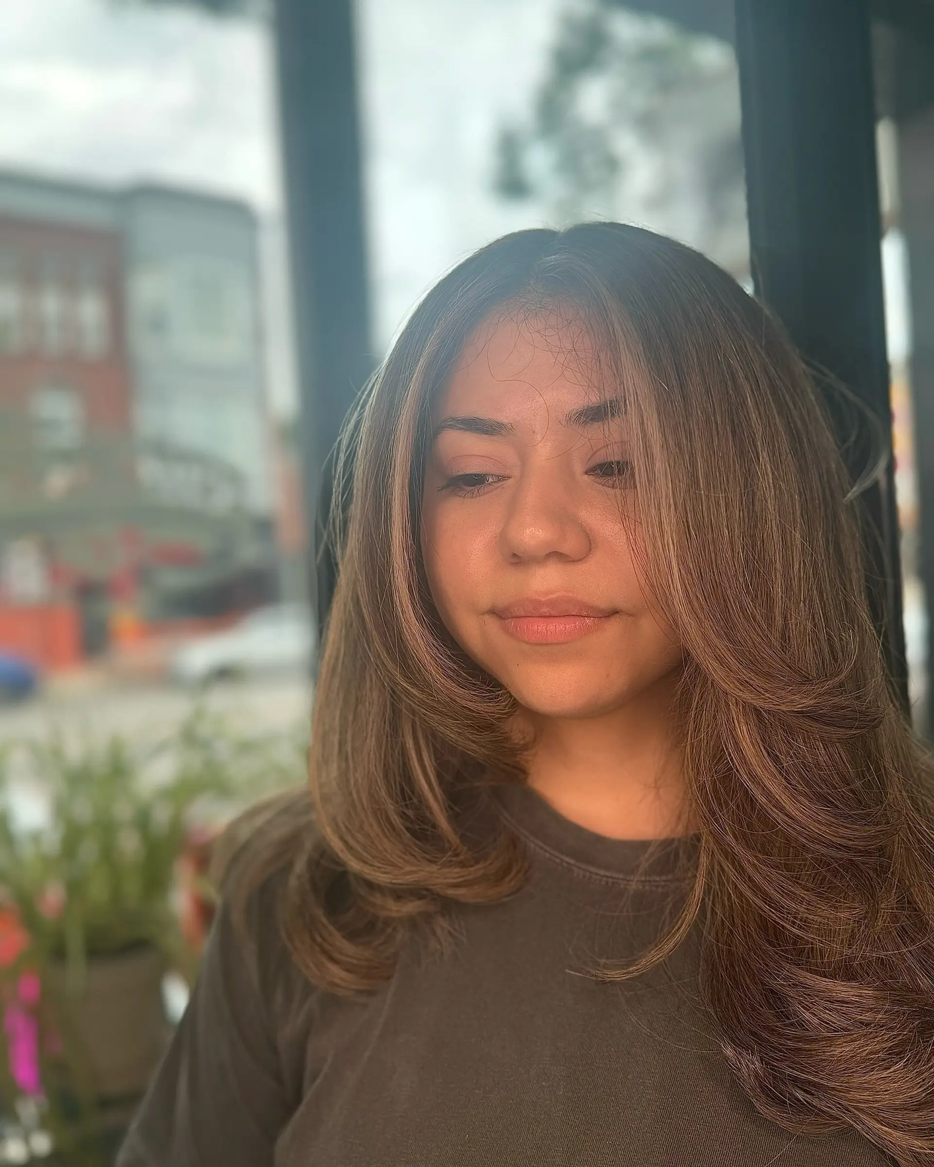 Long dimensional brown hair cut with soft face-framing layers and styled into a polished, voluminous blowout. 1