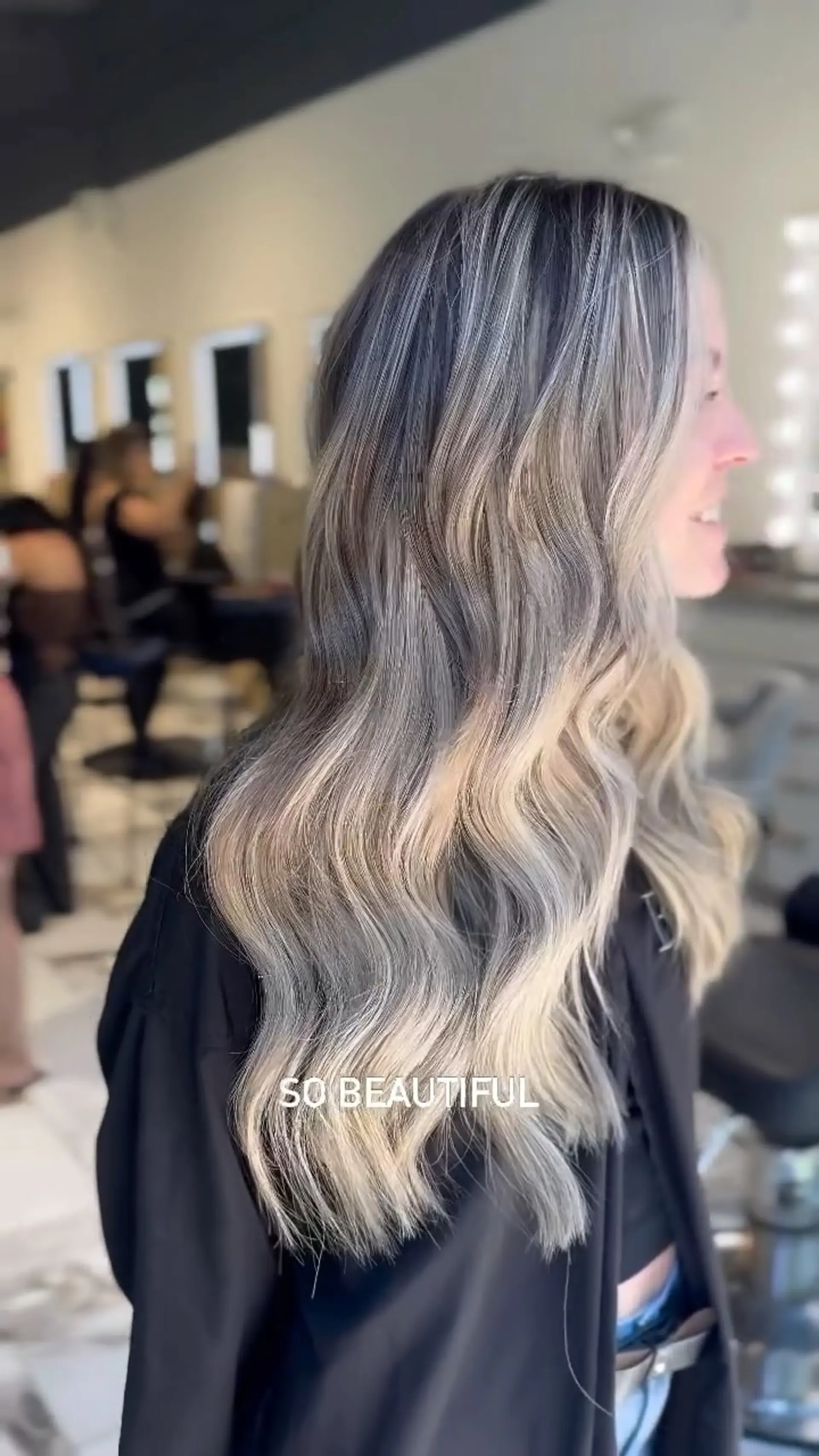 Long cool-toned ash blonde hair enhanced with custom weft extensions and styled into soft, flowing waves. 1