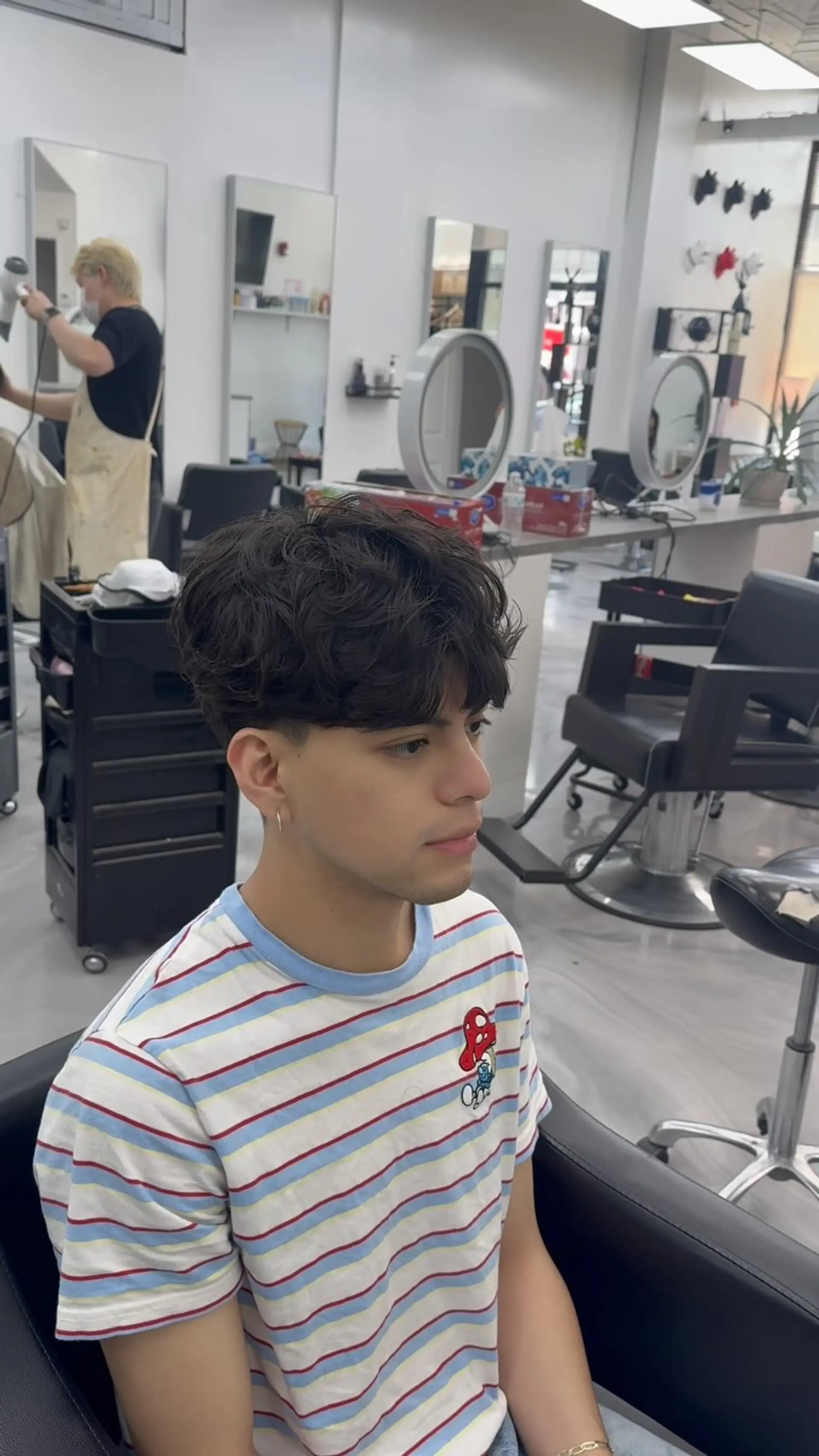 A modern short men's crop haircut featuring a textured, wavy top with forward-styled fringe and a clean taper fade. 1