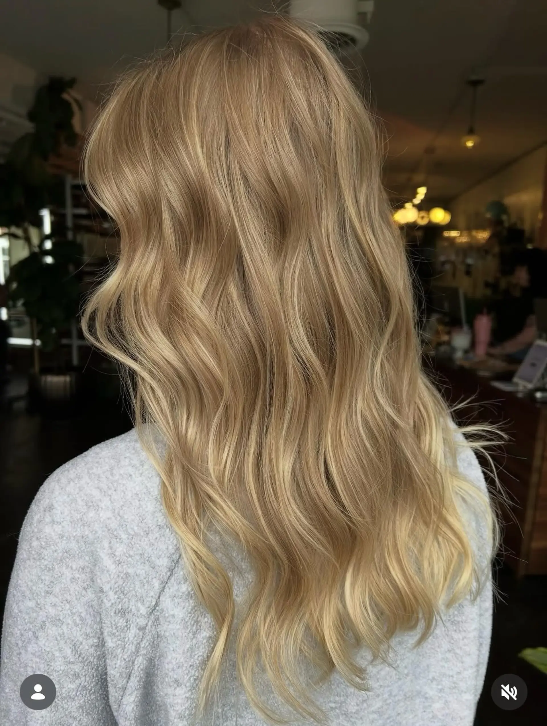 Long warm golden blonde hair styled in relaxed, flowing waves with dimensional highlights. 1