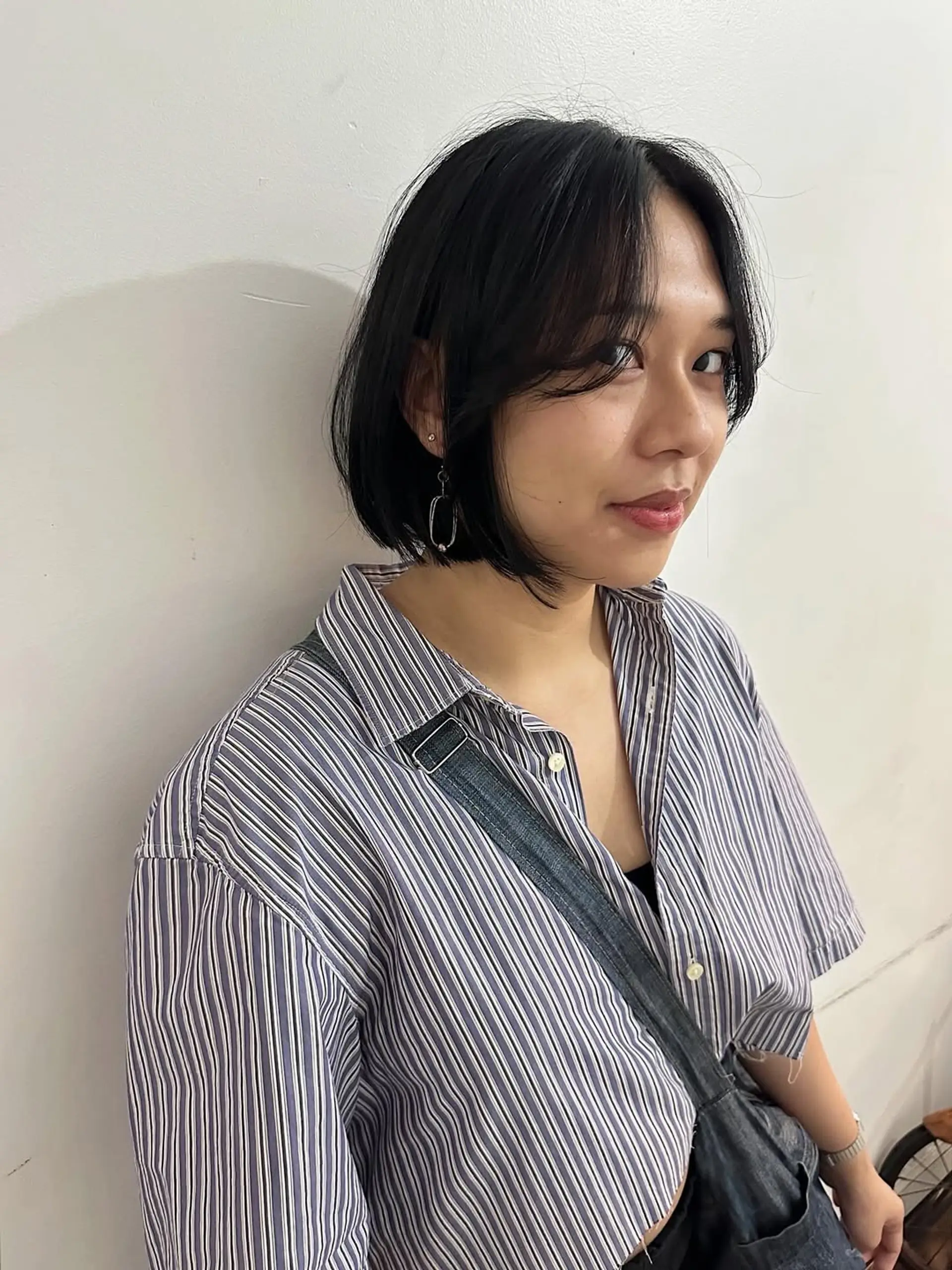 A chic short bob haircut, reaching chin-length, styled with soft wispy bangs and subtle face-framing layers. It's a modern and sleek look that beautifully frames the face. 1