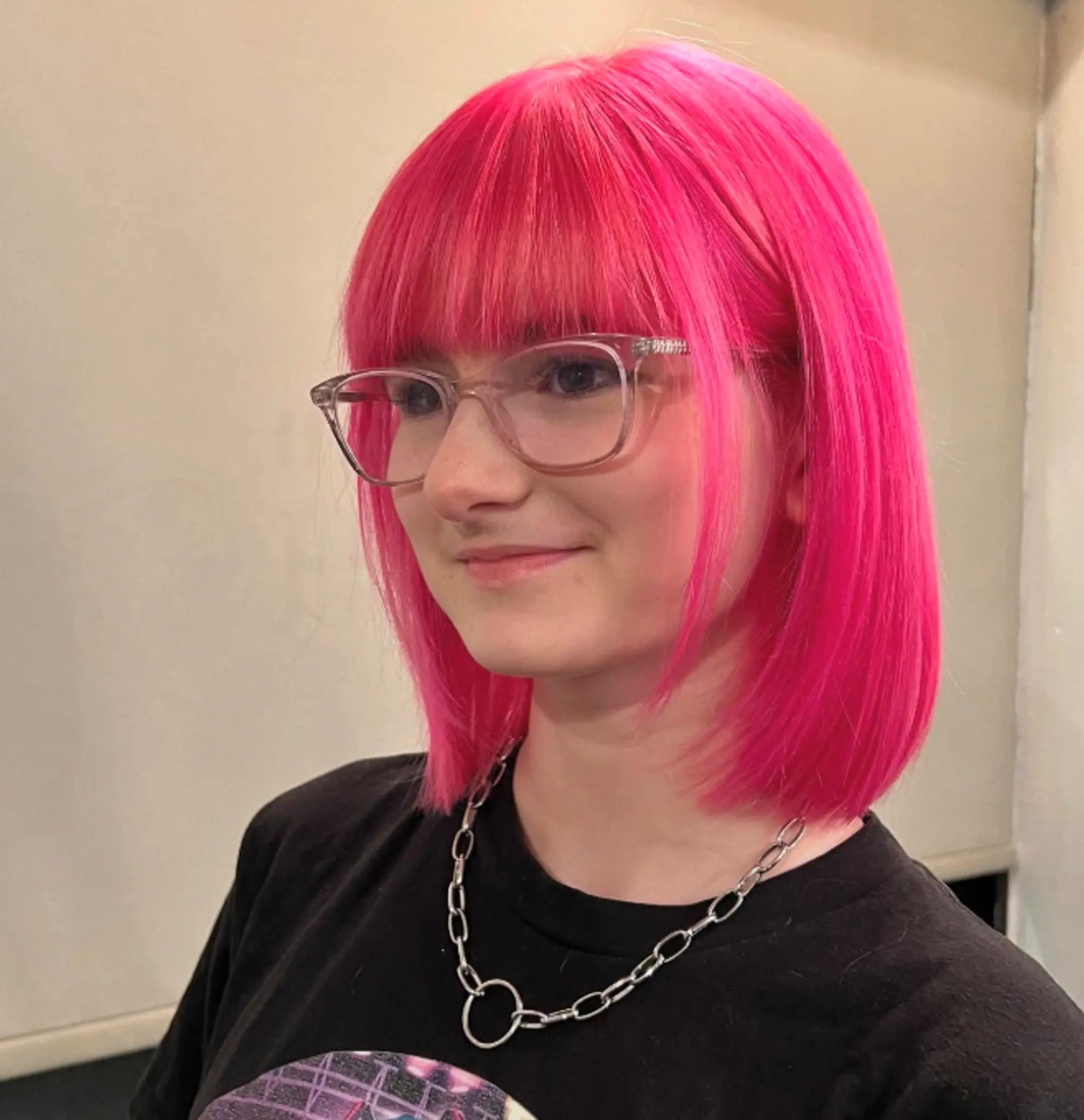 A blunt bob haircut with straight bangs and a vibrant pink color.