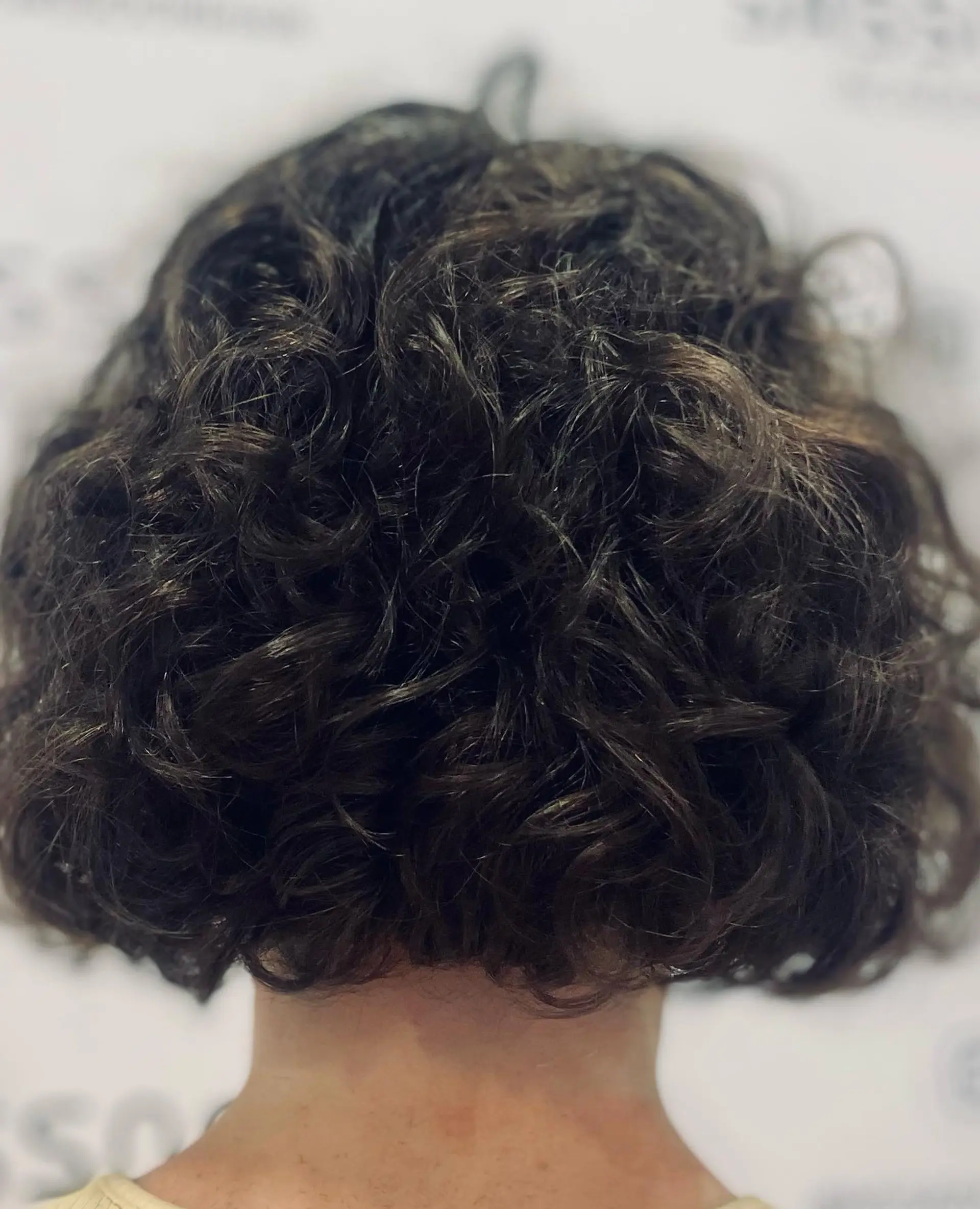 A short, neck-length curly bob cut showcasing dense natural curls with structured volume. 1