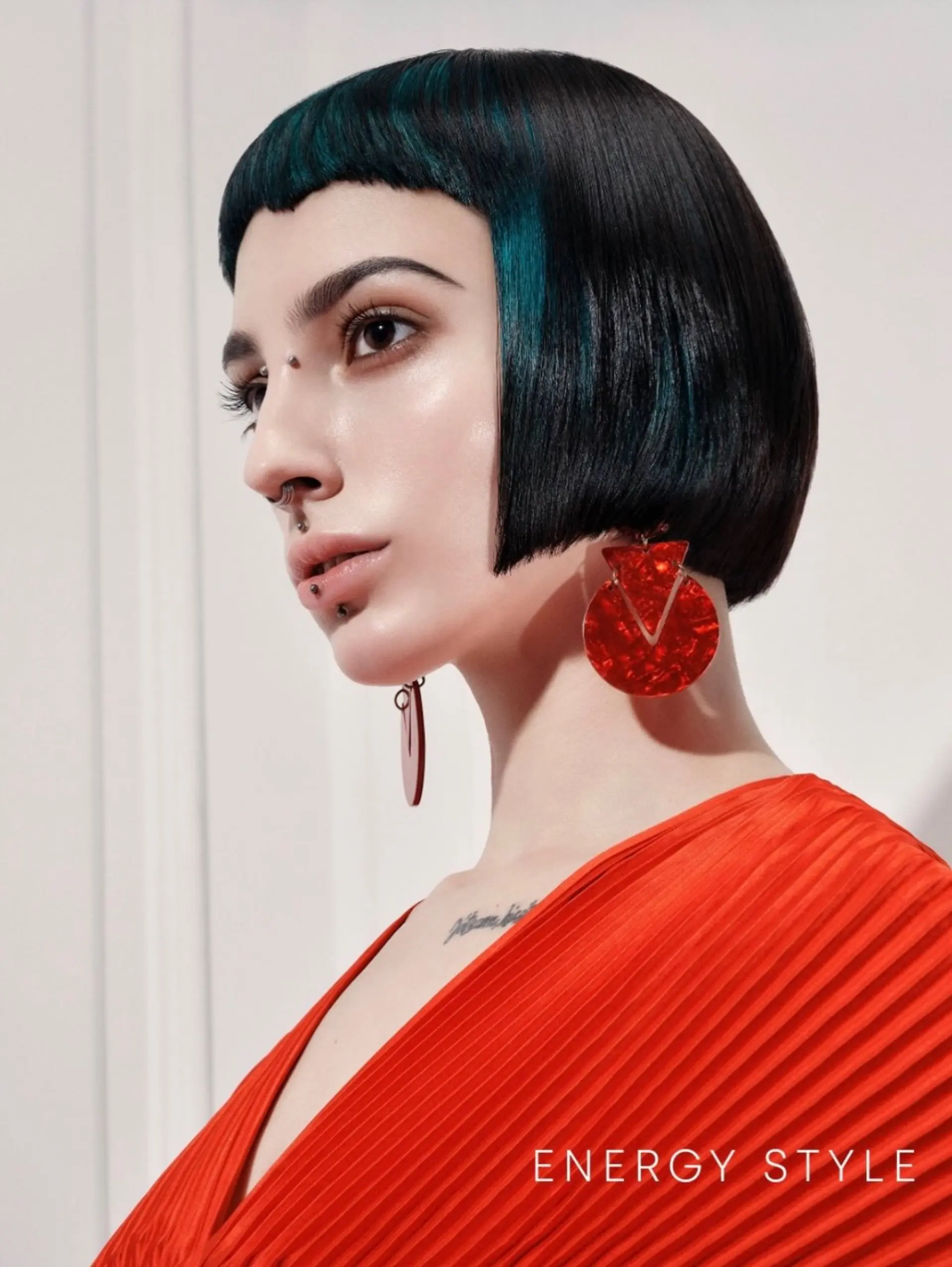 A sleek, geometric blunt bob cut cleanly at the jawline paired with sharp micro bangs and deep teal color accents. 1