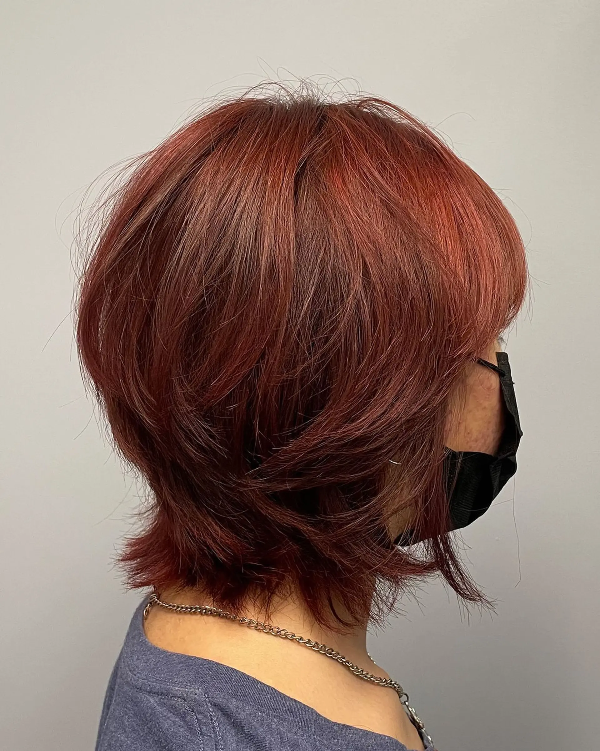 A feathered, graduated bob featuring soft textured layers and subtle flipped ends in a rich auburn-copper shade. 1