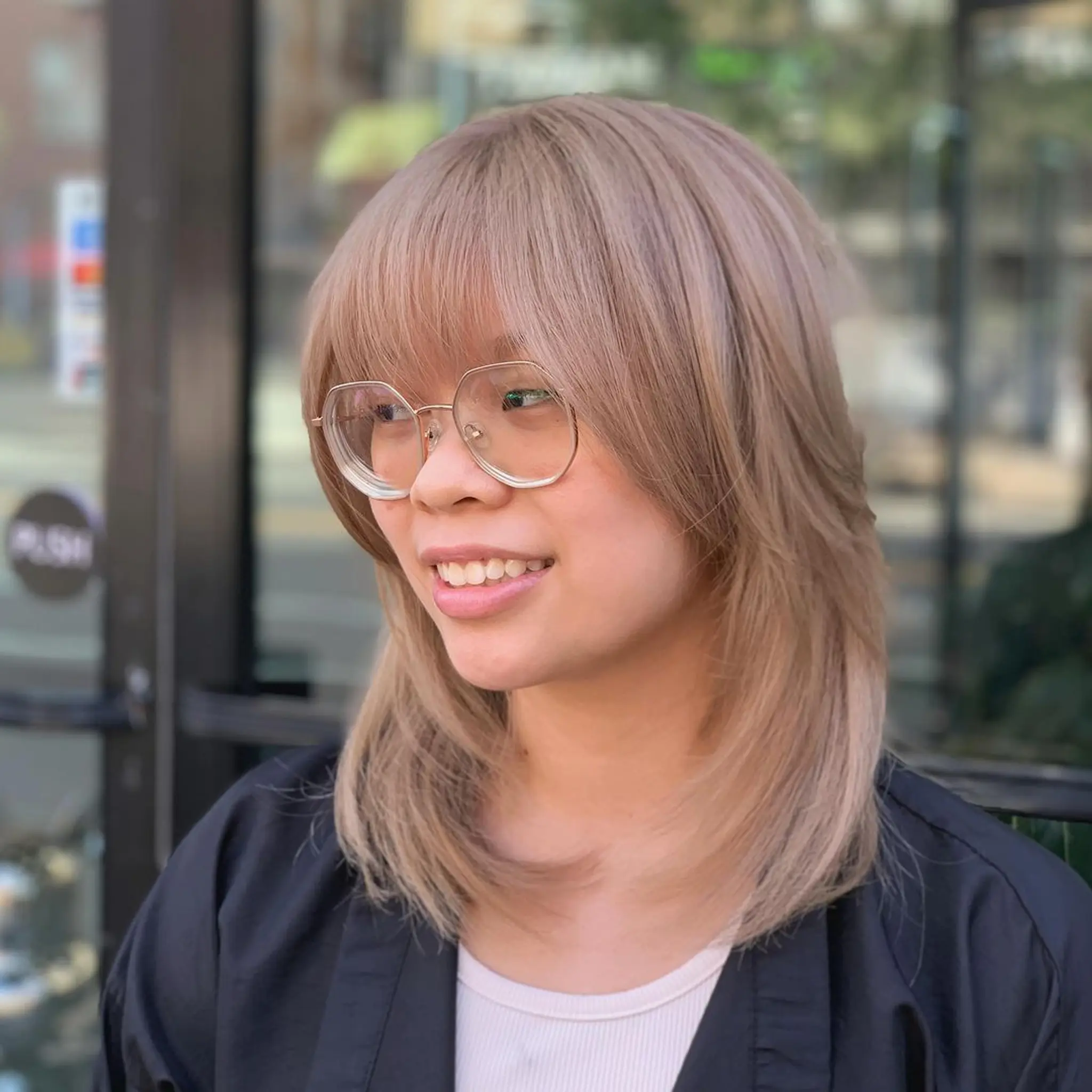 Medium-length ash blonde hair with layers that create a feathered, light appearance. Side-swept bangs frame the face, adding a youthful and trendy look. The hair is straight with a natural shine and sleekness.
Stylist - @xcellent_jason