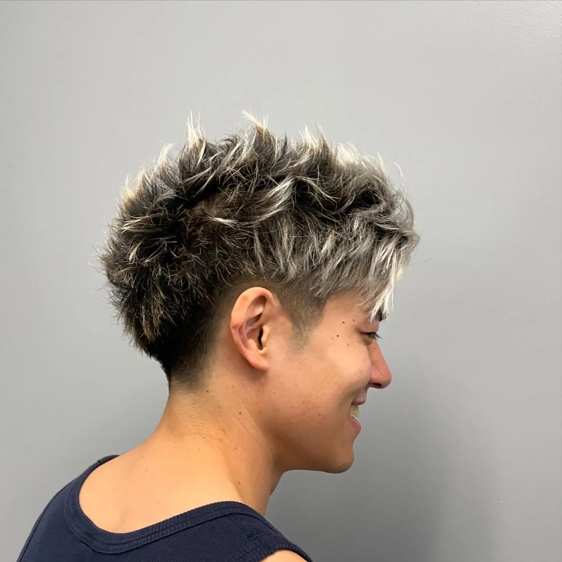 A textured short spiky haircut featuring frosted tips and a clean taper fade around the sides and nape. 1