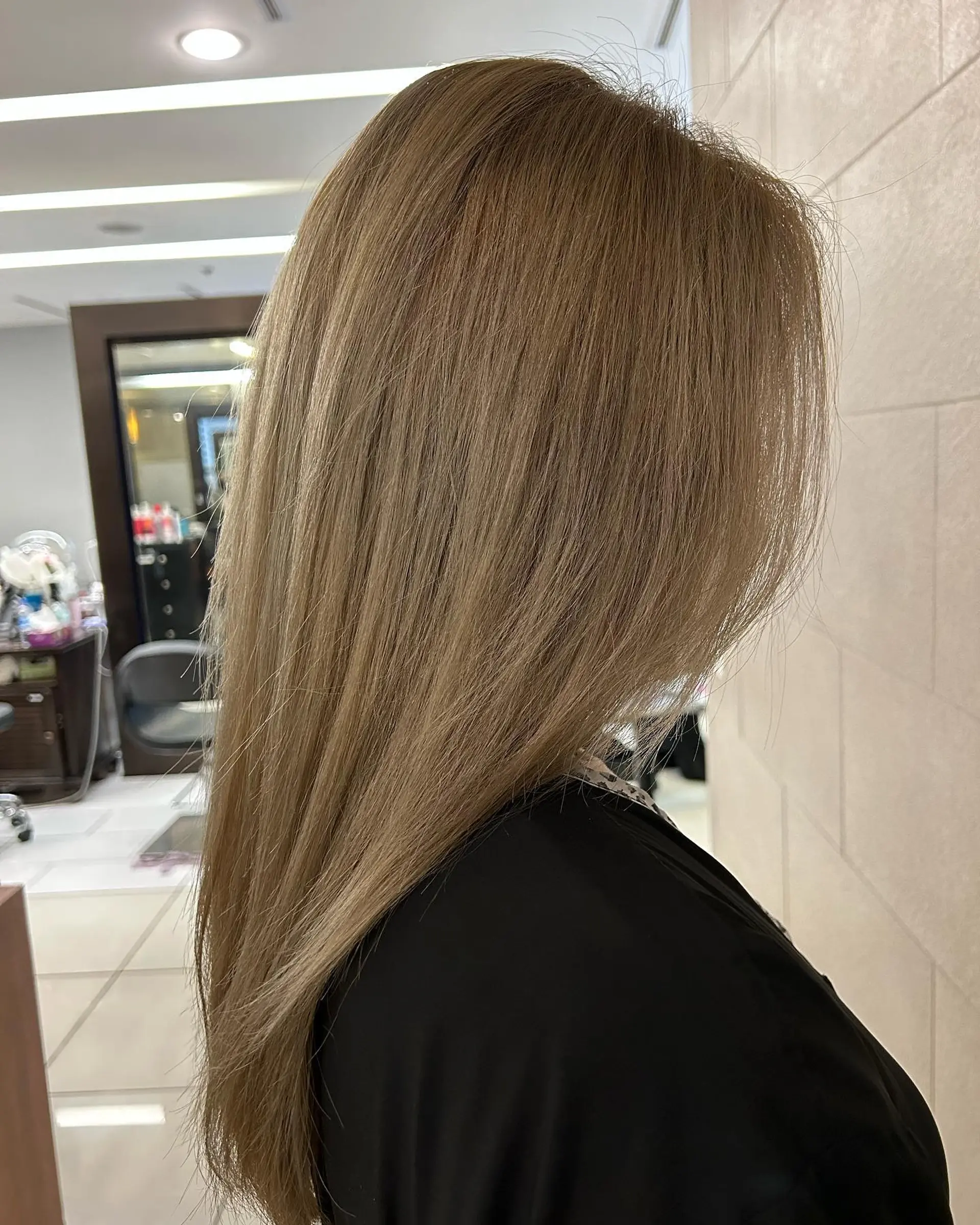 Long, sleek straight hair styled with a smooth blowout in a soft light ash brown shade. 1