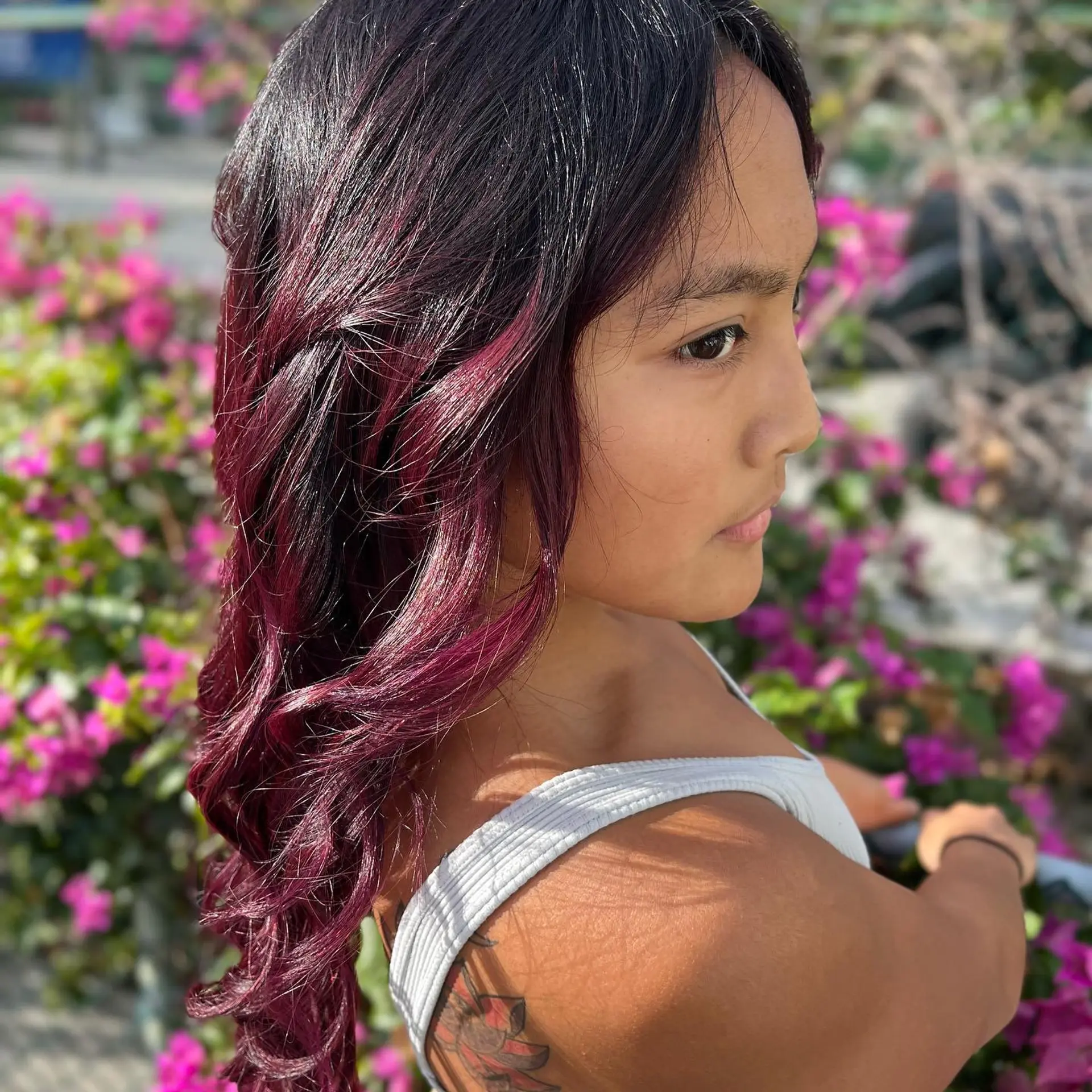 Long, wavy hair with a trendy burgundy color and dark roots. 5