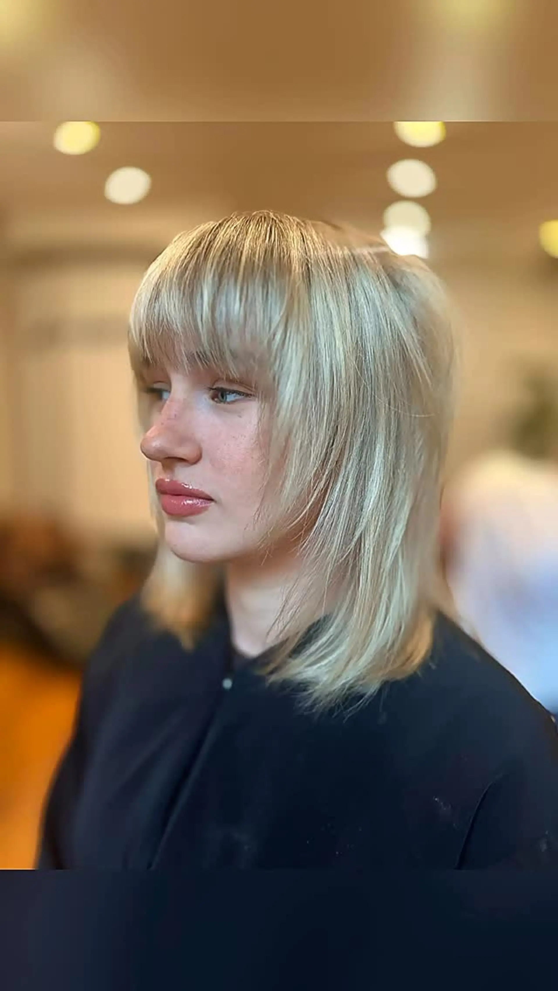 Medium-length feathered blonde shag haircut with soft face-framing layers and textured full bangs. 1