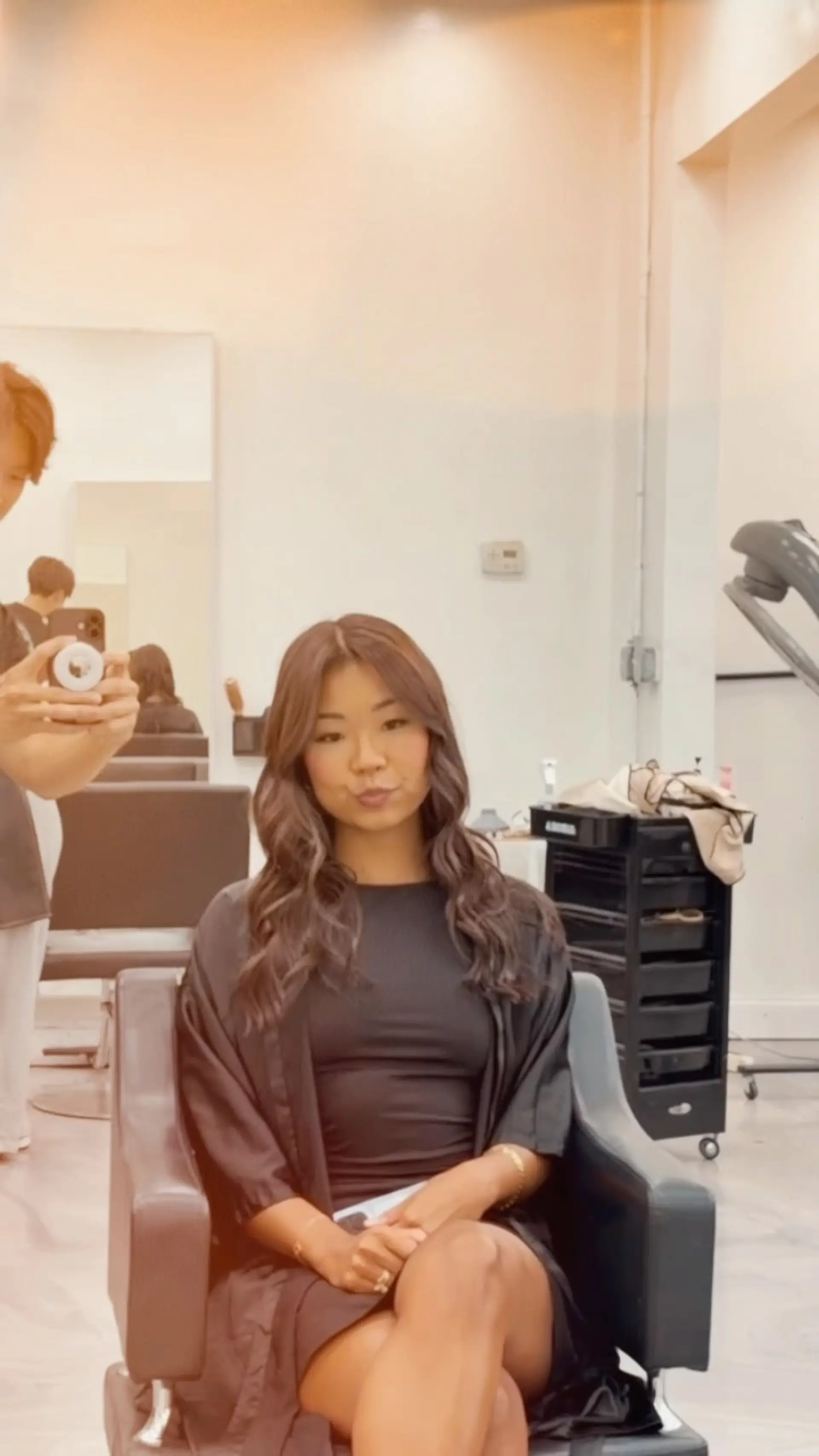Long chestnut brown hair styled with a center part into voluminous, soft waves. 1