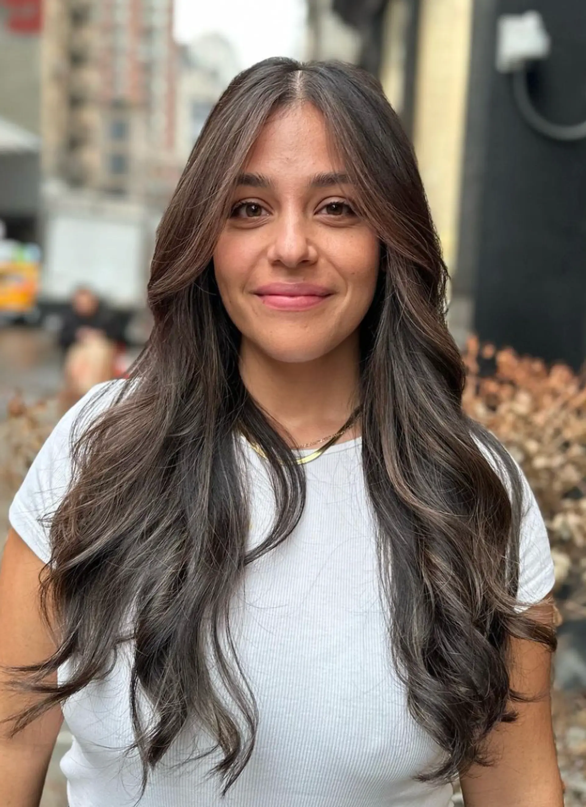 Dark brown, long, wavy hair with face-framing layers and a middle part for a natural, polished look. 1