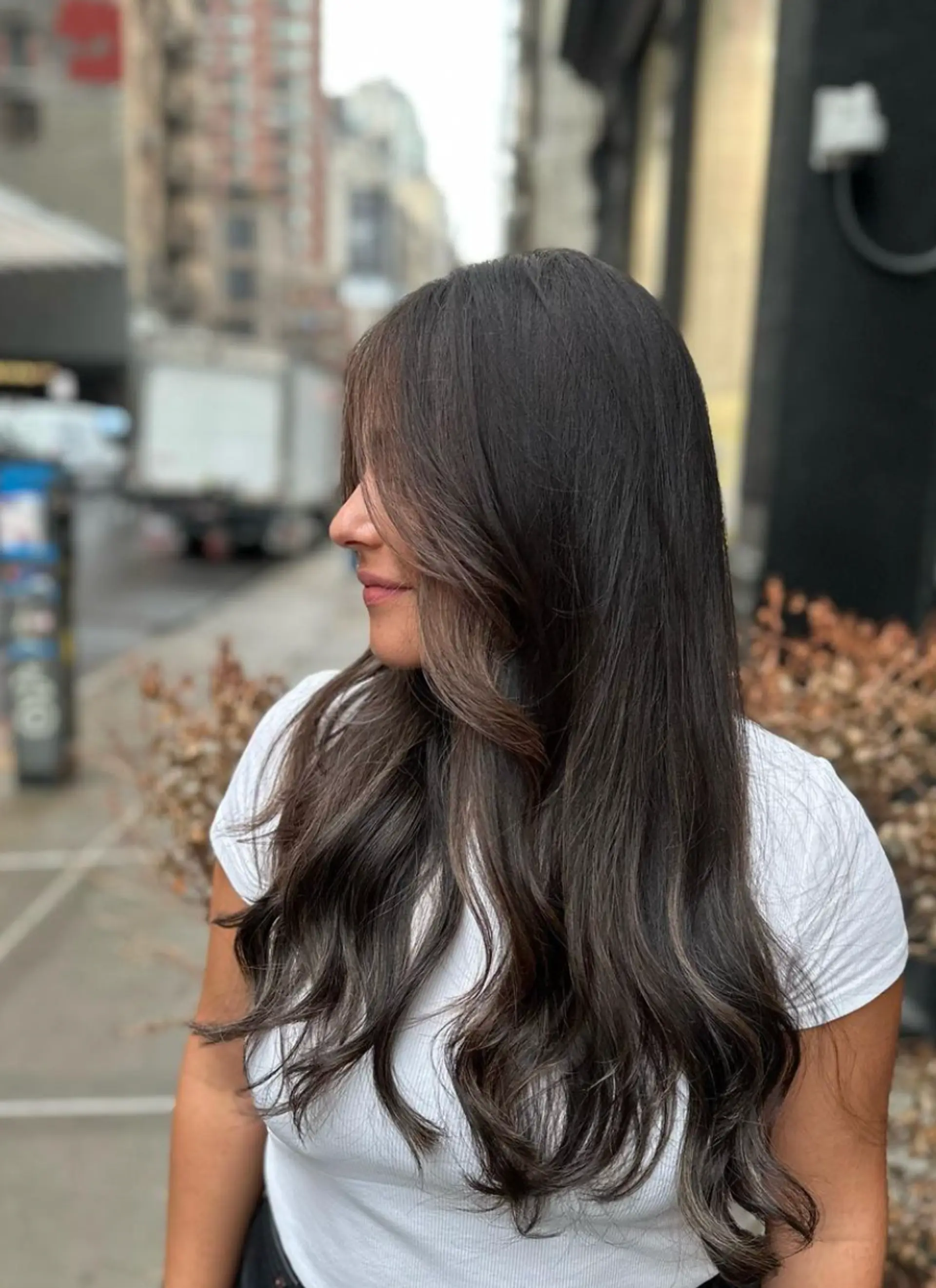 Dark brown, long, wavy hair with face-framing layers and a middle part for a natural, polished look. 2