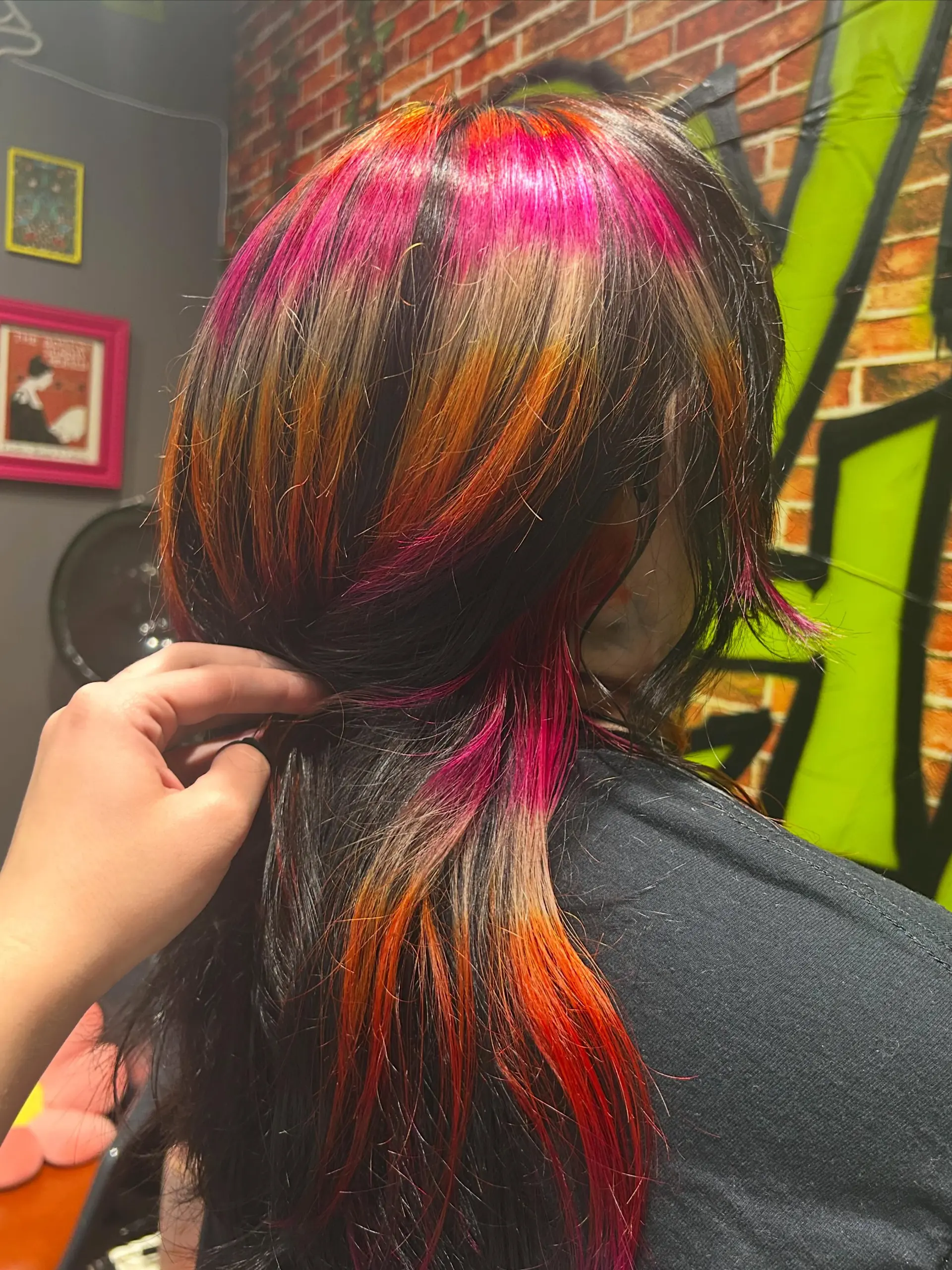 Medium-length dark hair customized with horizontal vivid bands of hot pink, bright orange, and warm blonde. 1
