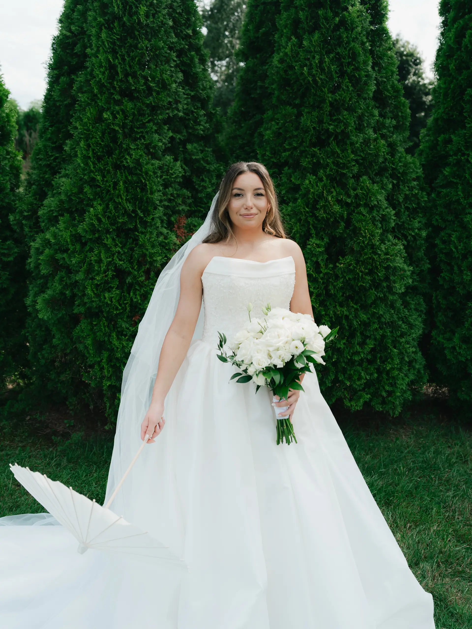 Long brunette hair styled in soft, natural waves parted down the middle, beautifully paired with a delicate bridal veil. 1
