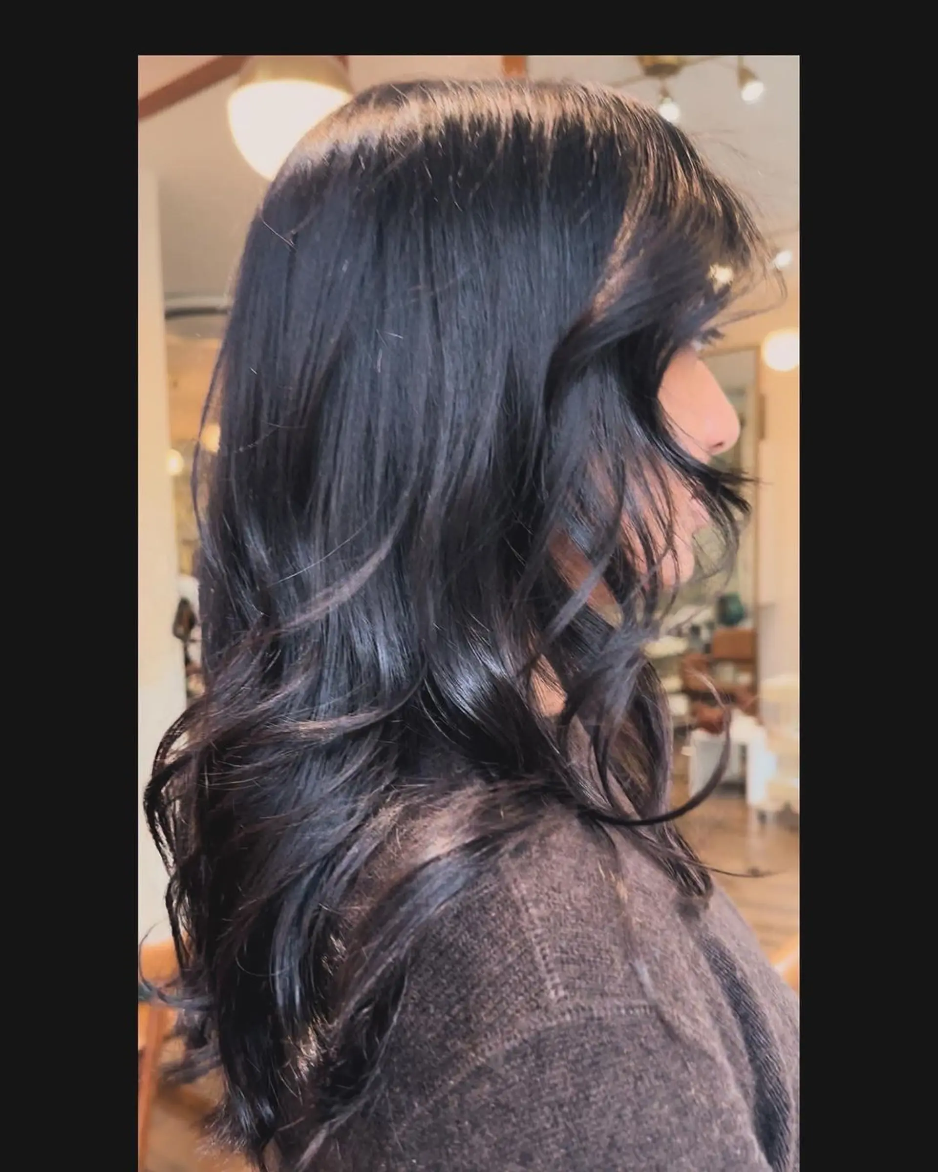 Long, wavy, black hair with a glossy finish and a side part, styled in soft waves. 1