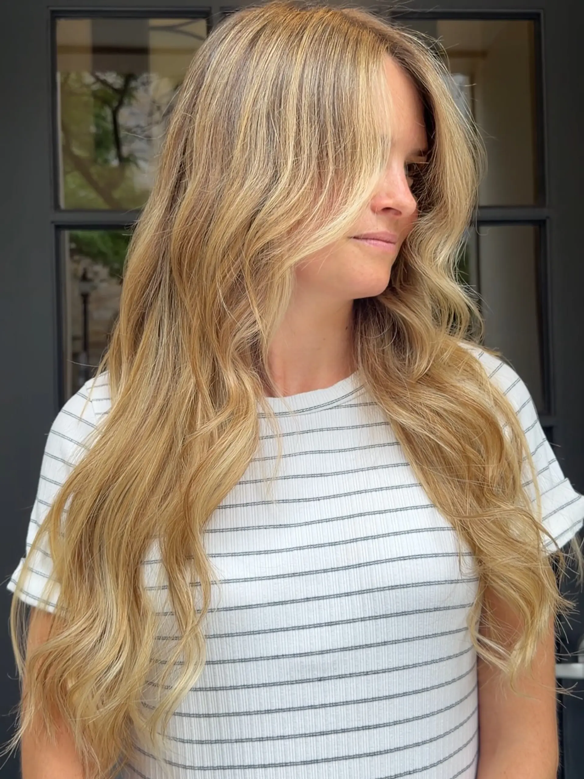 Long, flowing warm blonde hair styled with seamless dimensional highlights and soft, effortless waves. 1