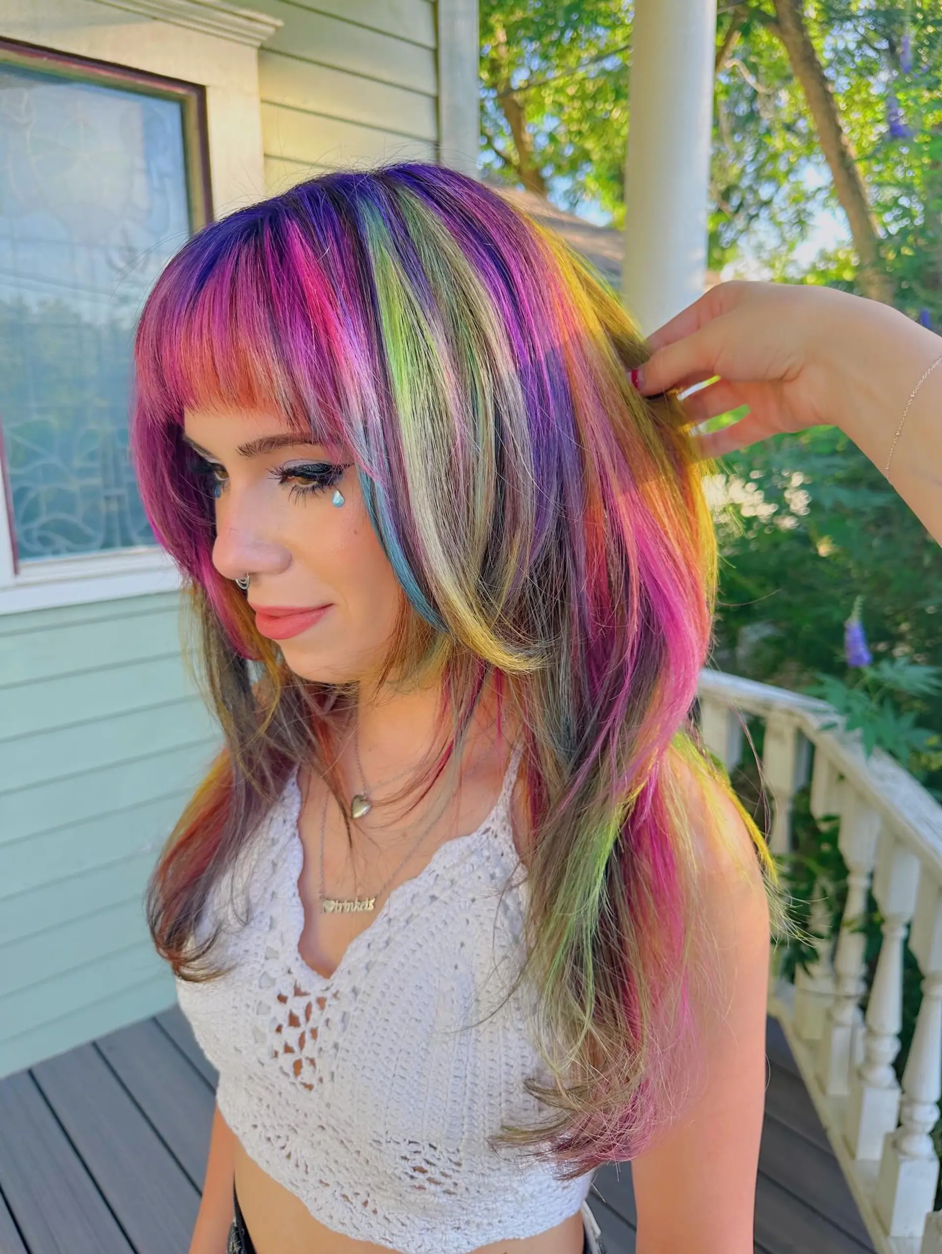 A vibrant and playful medium-length straight hairstyle featuring a full rainbow vivid color transformation. It's cut with face-framing layers and includes a bold, multi-tonal fringe for a distinct, edgy aesthetic. 1