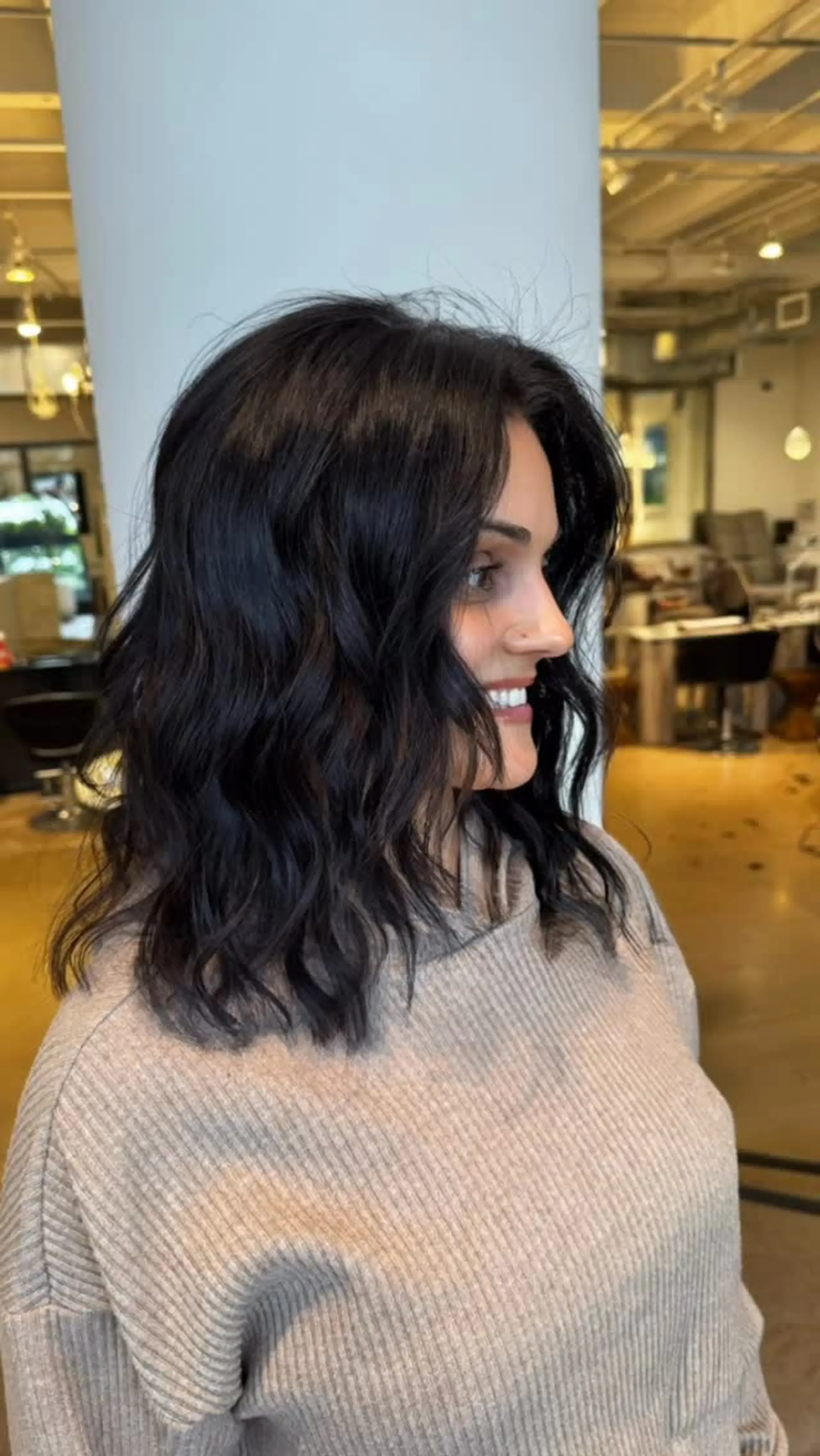 A shoulder-length wavy lob featuring relaxed tousled waves, a center part, and soft face-framing layers in a deep espresso brown. 1