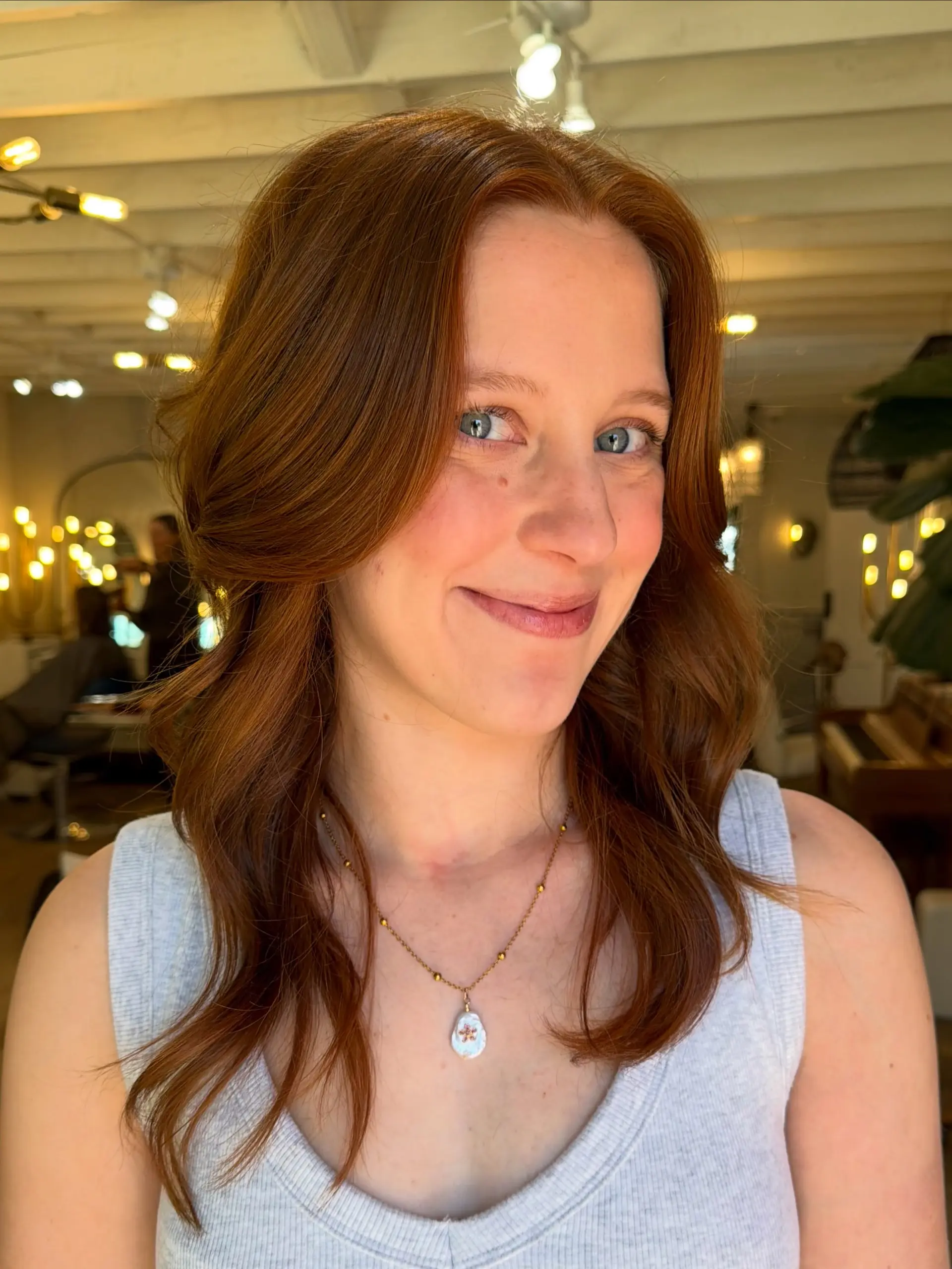 Medium-length warm copper hair cut with soft face-framing layers and styled in gentle waves. 1