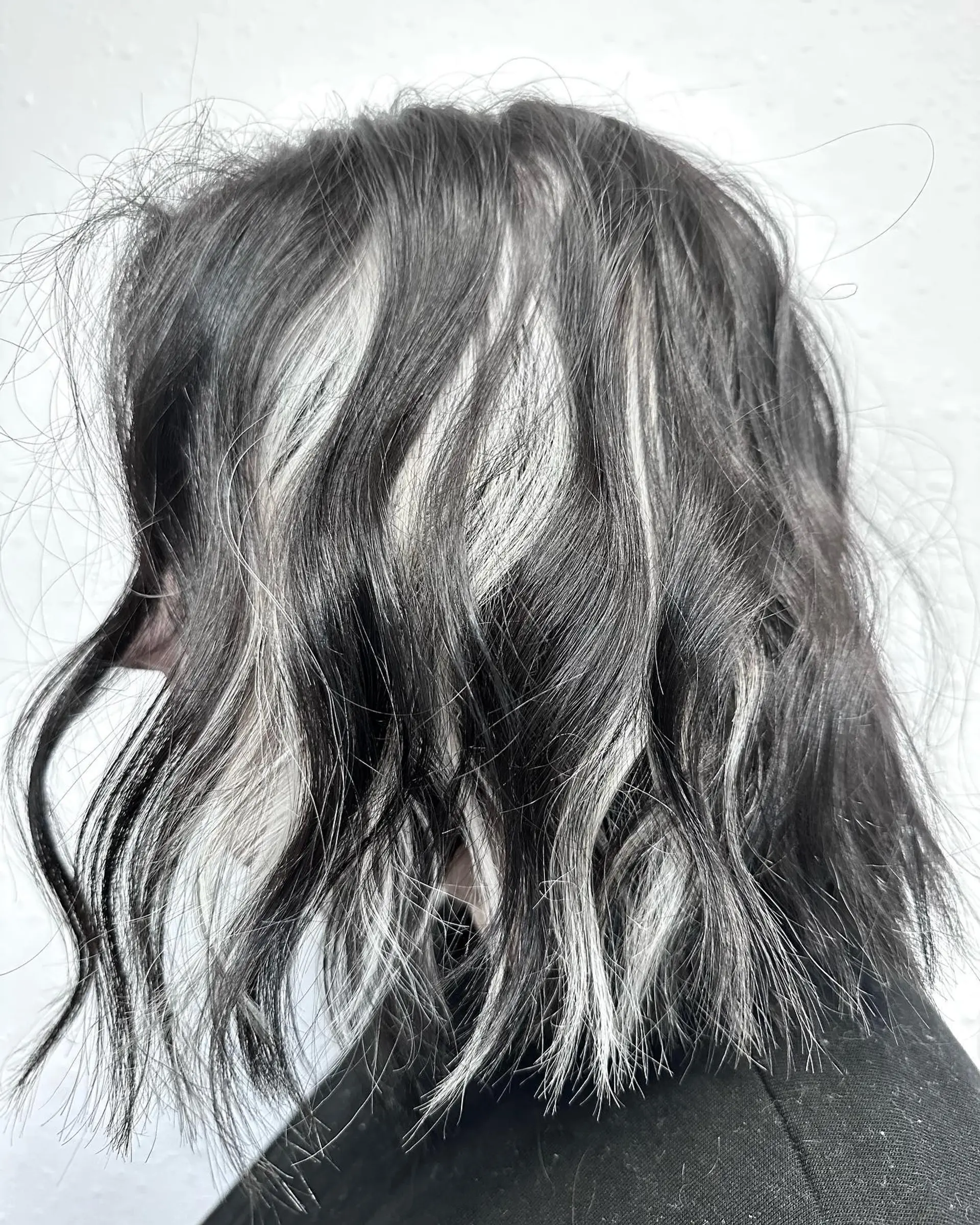 A textured shoulder-length bob showcasing bold platinum white peek-a-boo highlights beneath a jet black top layer. 1