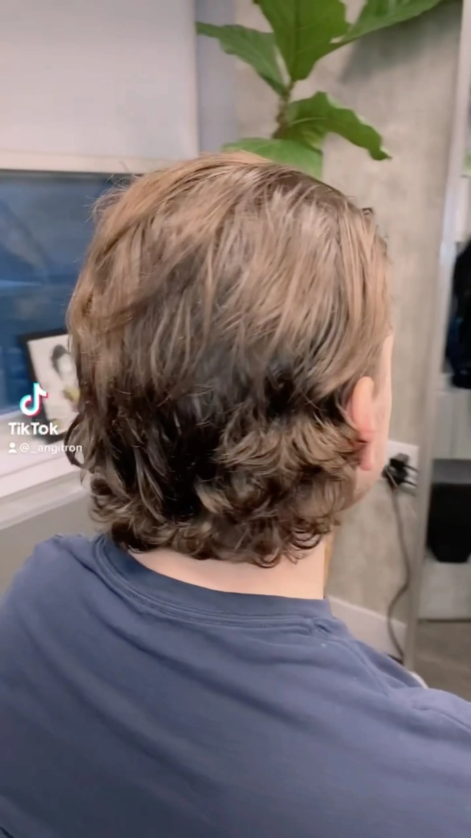 Medium-length layered flow haircut featuring natural waves tapered softly at the neckline. 1