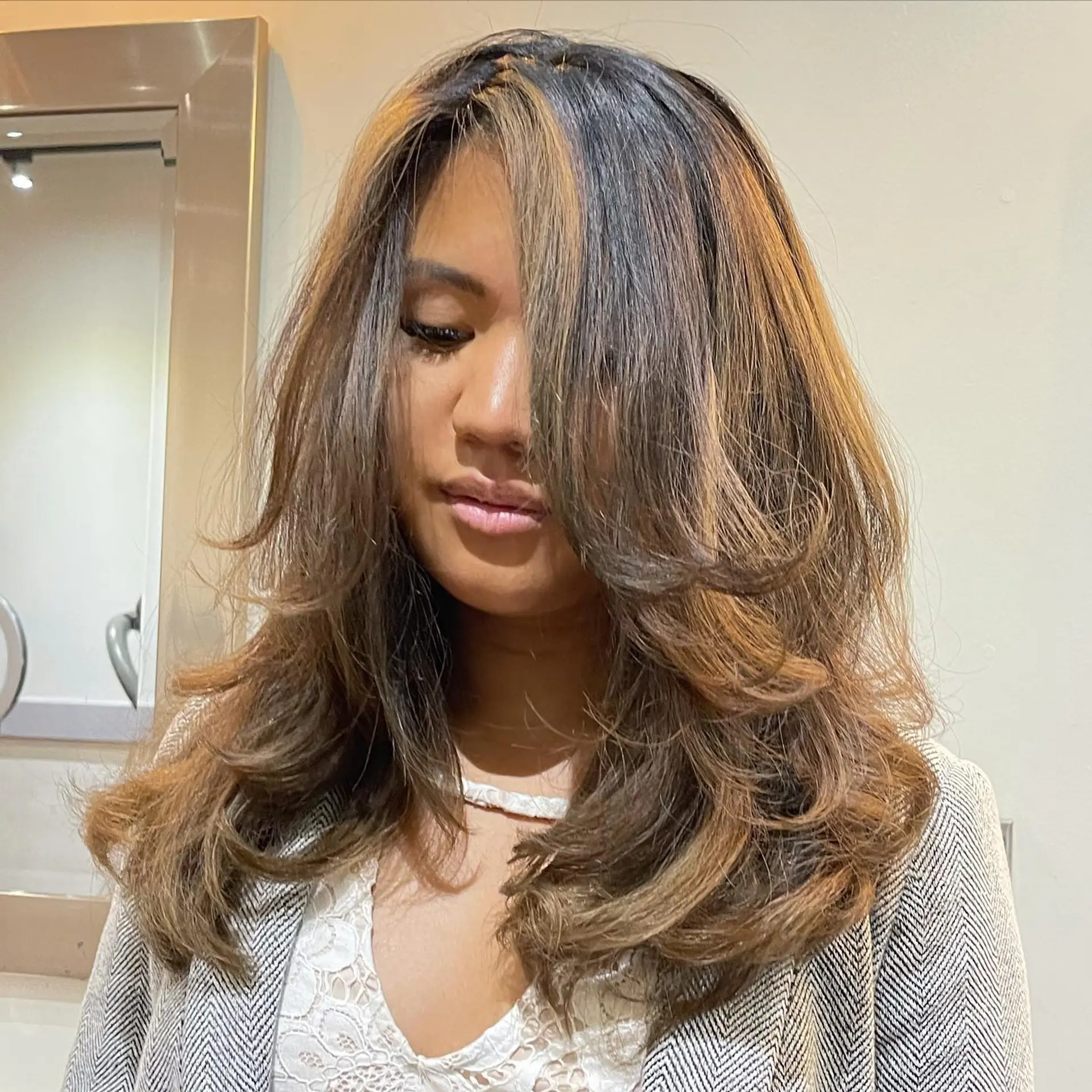 Voluminous, face-framing layered cut styled with a bouncy blowout and feathered curtain bangs. 1