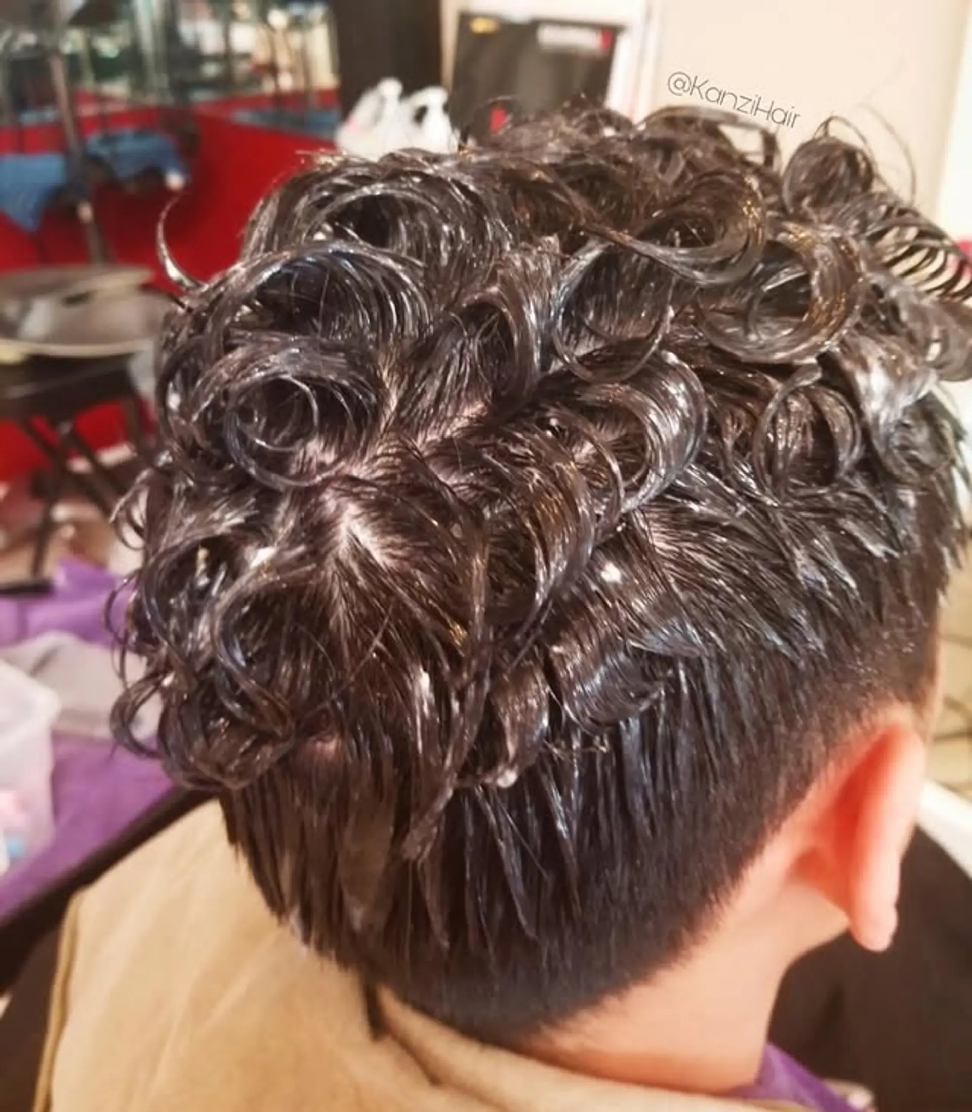 A fashionable men's perm style with distinct, voluminous curls concentrated on the top section of the head, complemented by clean, short hair on the back and sides, creating a dynamic contrast and a modern aesthetic. 1